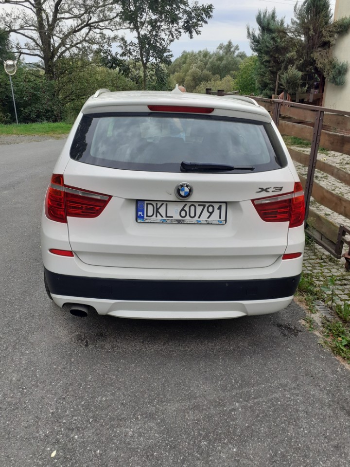 Biały samochód marki BMW X z polskimi tablicami rejestracyjnymi DKL 60791, widok z tyłu