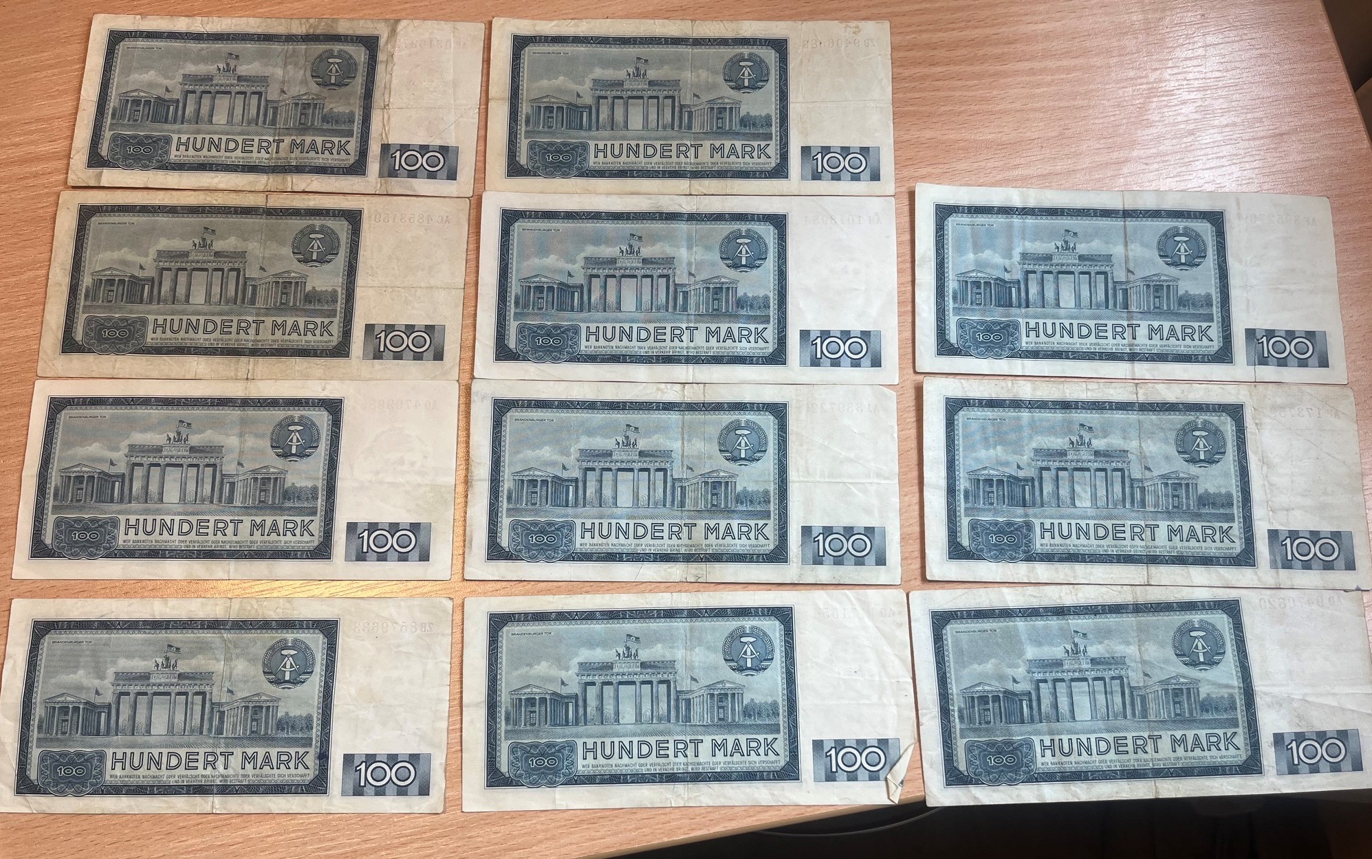 Odwrotna strona jedenastu banknotów o nominale 100 marek NRD z motywem Bramy Brandenburskiej.