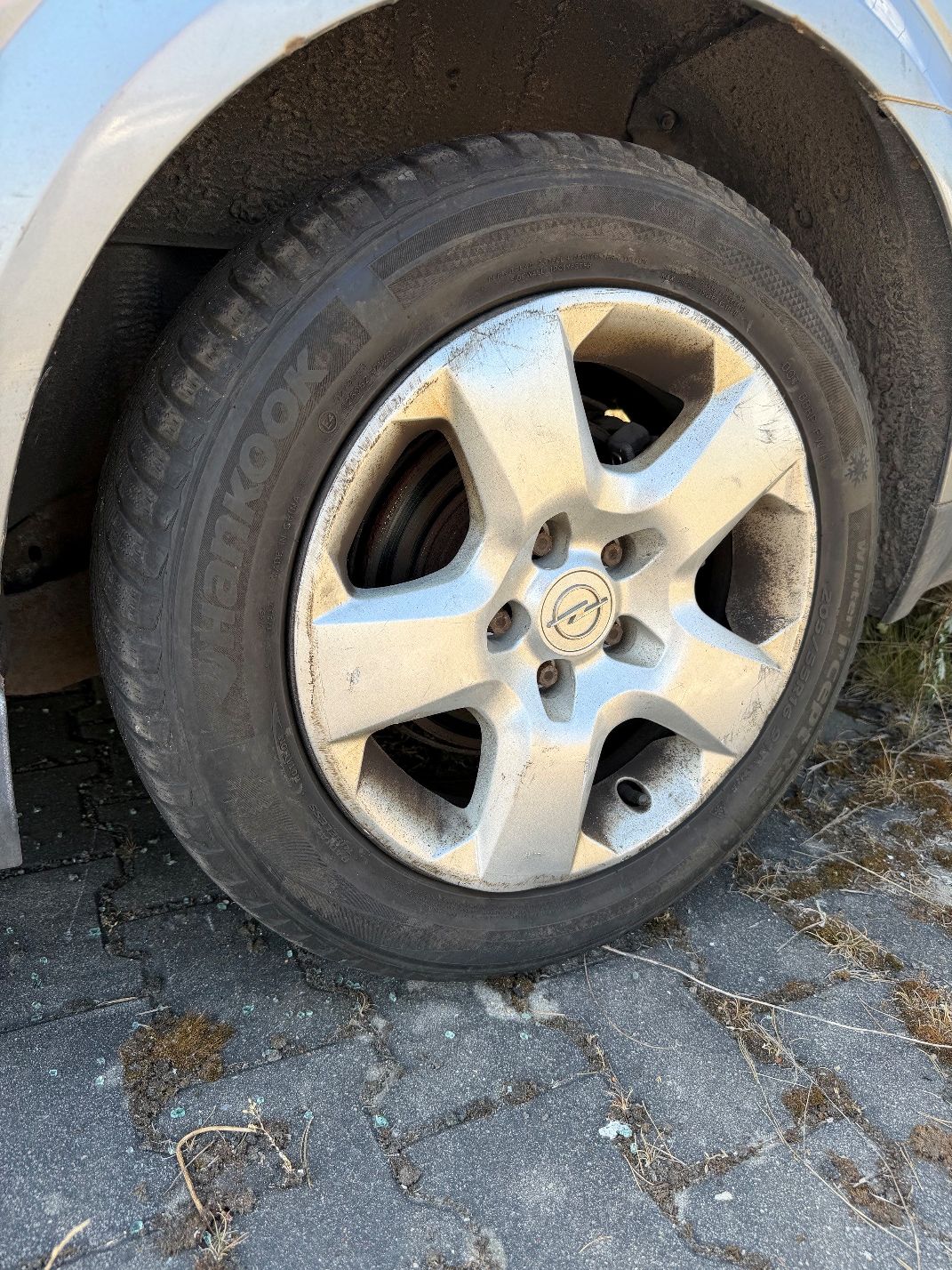 Szary Opel Vectra. Ujęcie felgi aluminiowej i opony.