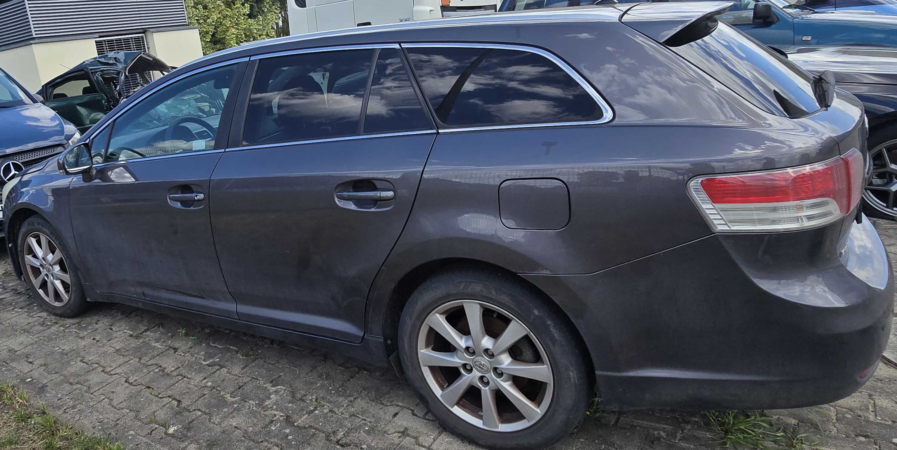 Lewy bok grafitowej Toyoty Avensis bez widocznych uszkodzeń
