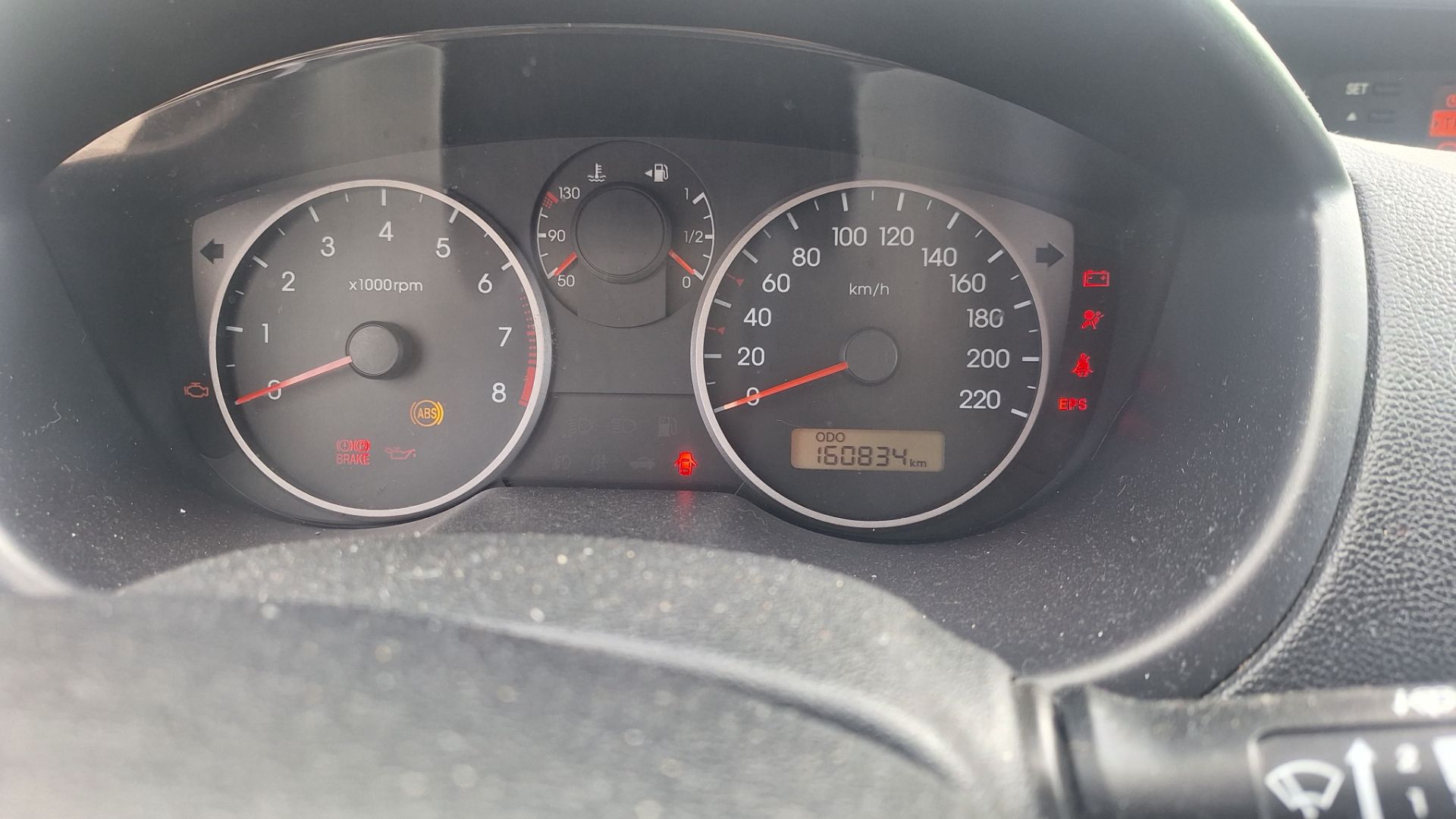 Wyświetlacz cyfrowy samochodu pokazujący przebieg 160834 km.