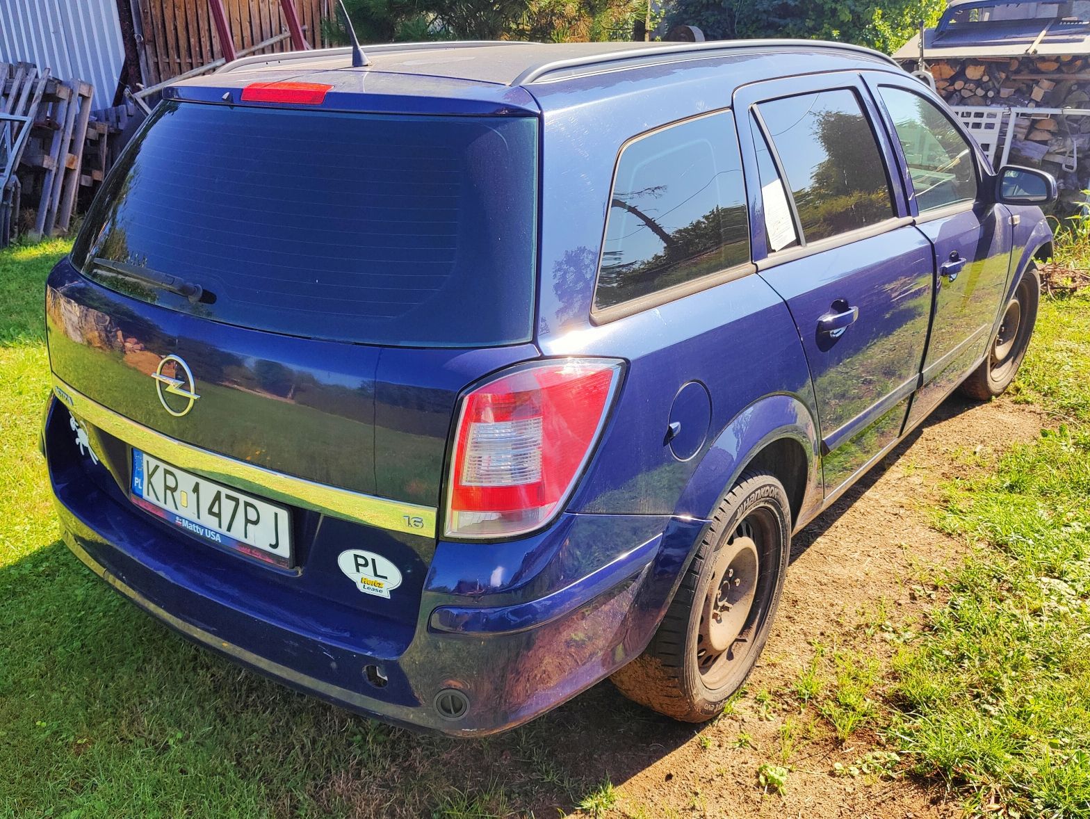 niebieski samochód osobowy typu kombi z widocznym zarysowaniem na drzwiach pasażera z prawej strony