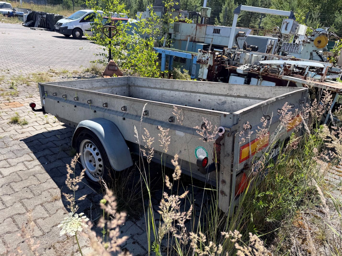 Przyczepa lekka Stema. Widok lewego tyłu. Wygięta burta tylna. Pęknięta lampa tylna prawa.