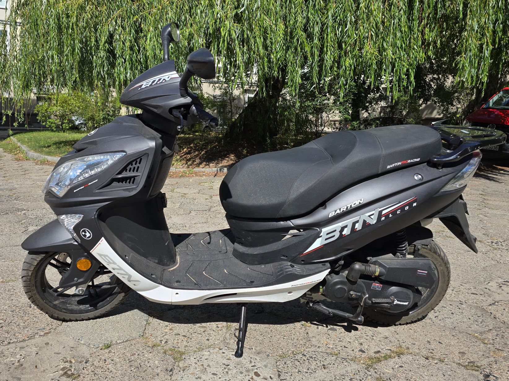 Motorower Zhongneng koloru czarno-białego. Widok z lewej strony, z profilowaną kanapą i widocznymi logotypami na obudowie