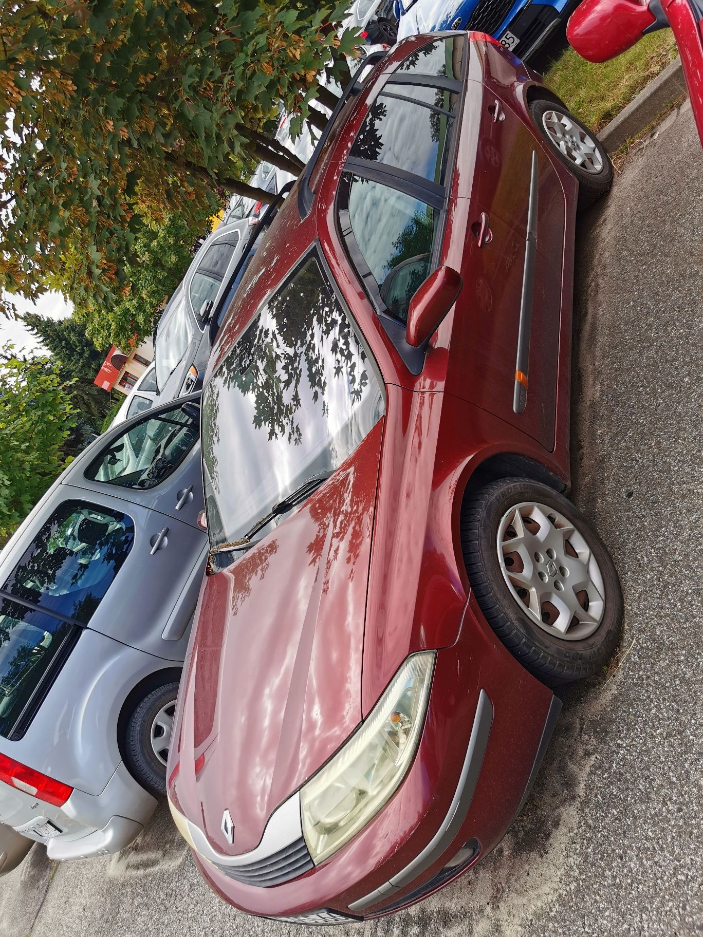 Samochód osobowy marki Renault Laguna kombi rocznik 2004 , kolor bordowy, widok z lewego przodu.