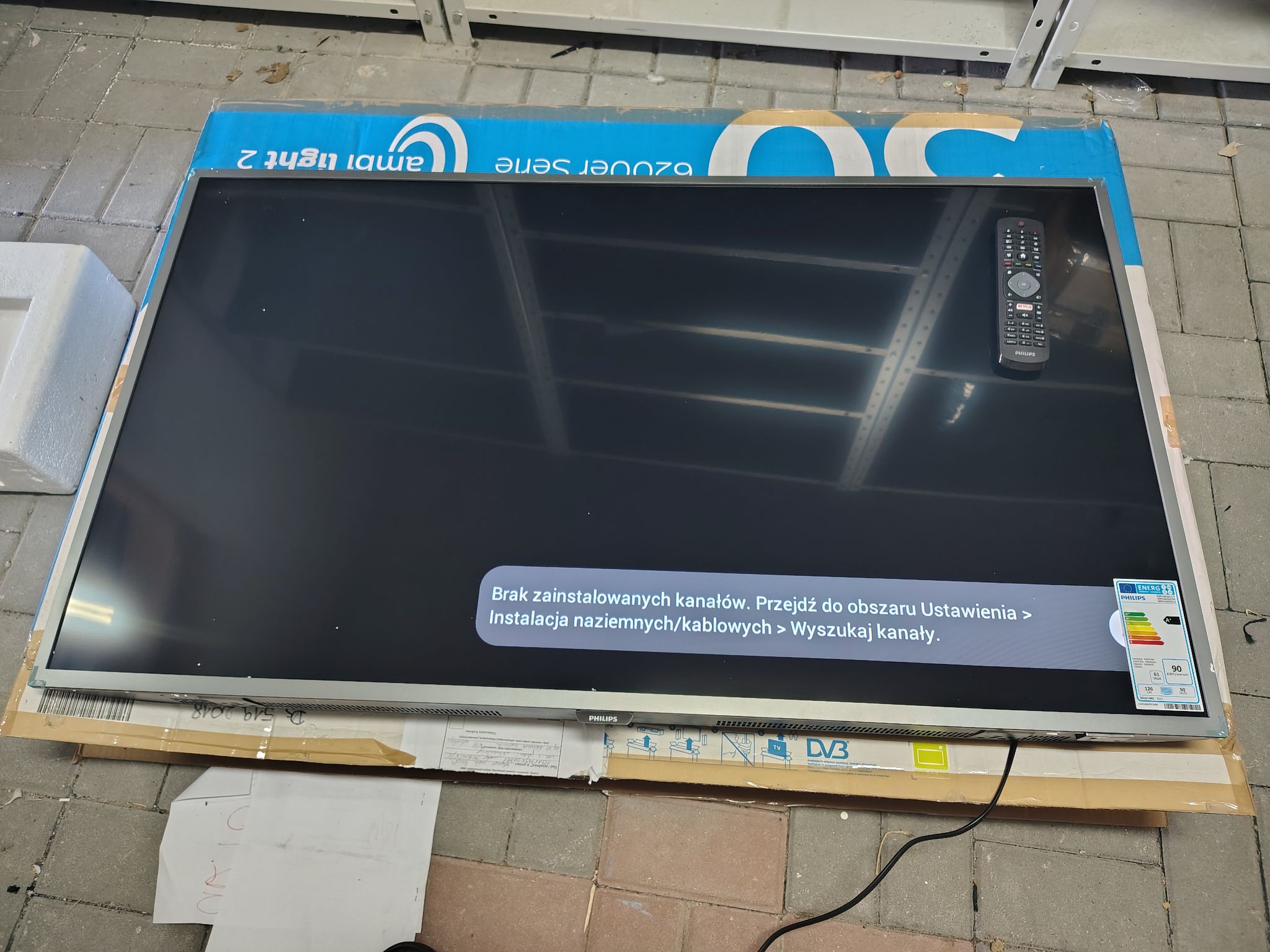 Telewizor_widok z przodu_wraz z pilotem i widocznym menu.