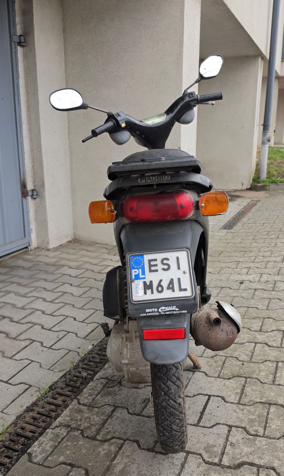 Motorower koloru czarnego. Widok z tyłu. Po bokach znajdują się kierunkowskazy. Nad błotnikiem mieści się tablica rejestracyjna