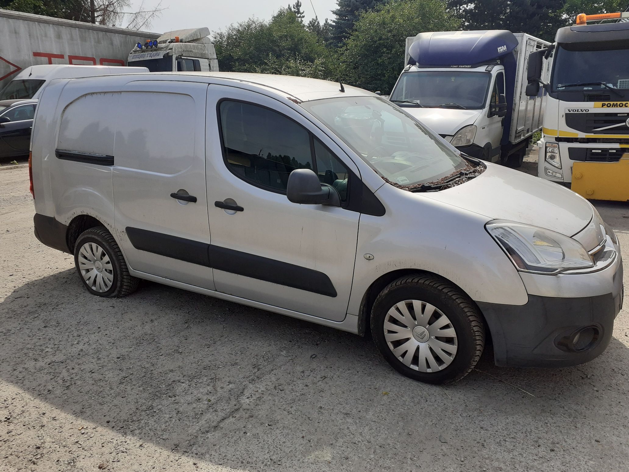 Srebrny Citroën Berlingo, ujęcie z boku od strony pasażera. Widoczne przesuwne drzwi, kołpaki i czarne listwy ochronne.