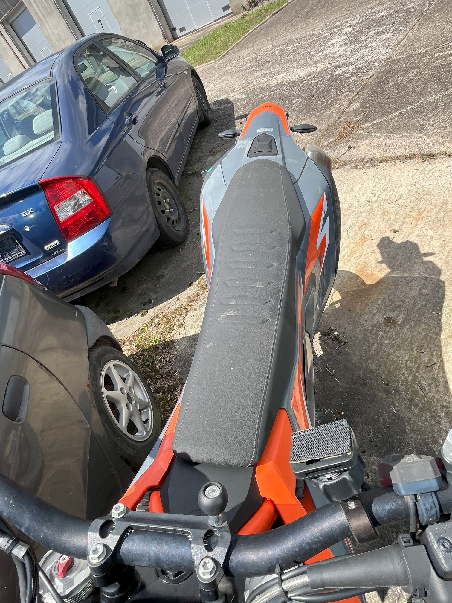 Widok z góry na siedzenie i kierownicę motocykla z widocznymi oznaczeniami i fakturą o sportowym charakterze