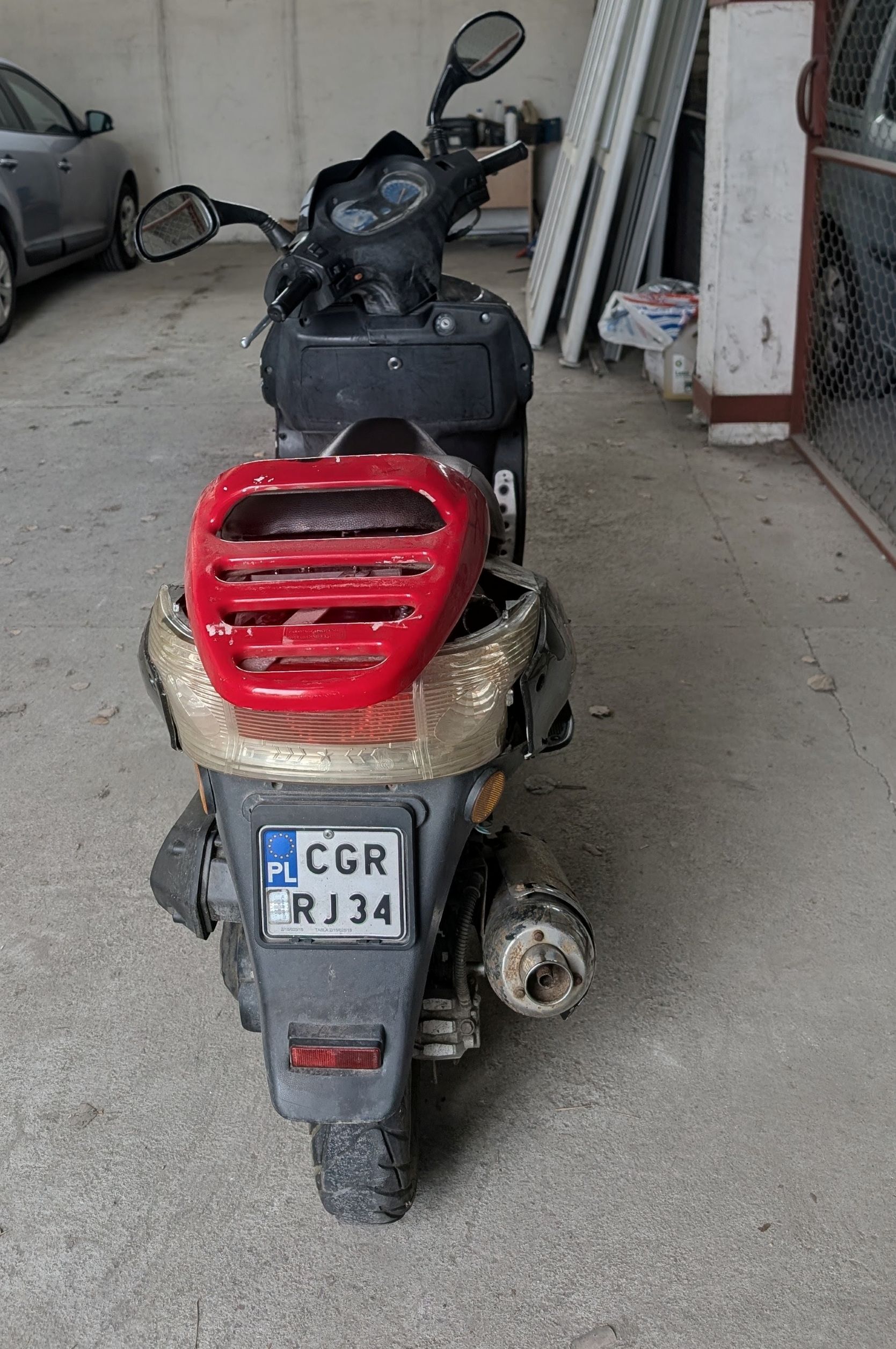 tył motoroweru z zamontowanym czerwonym bagażnikiem
