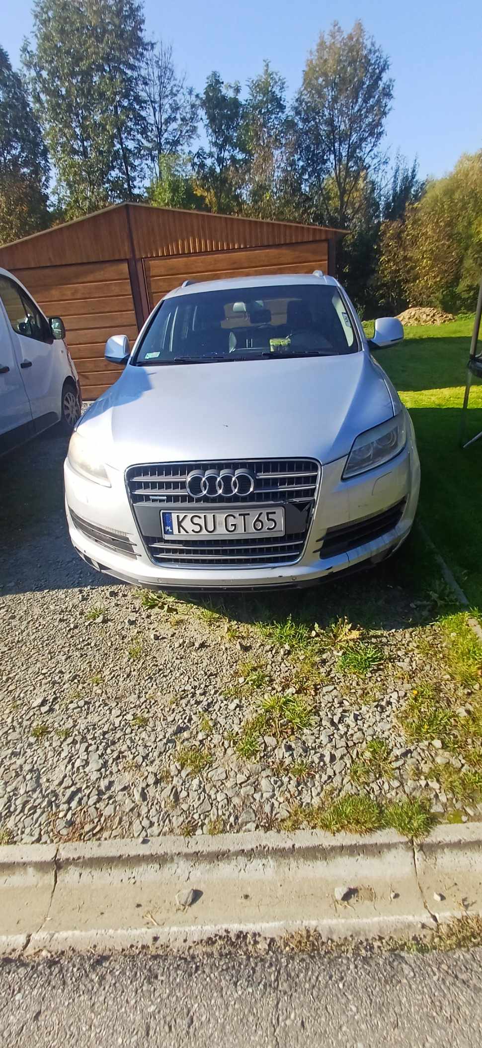 Zdjęcie przedstawia przód srebrnego samochodu z widoczną tablicą rejestracyjną.