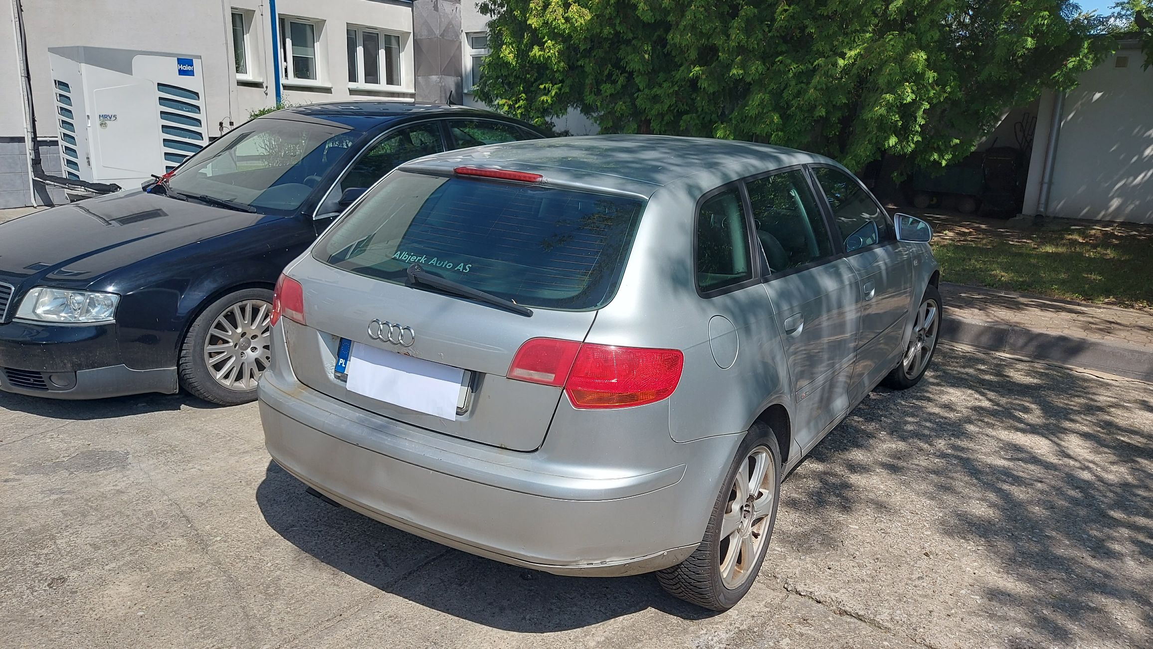 Widok na tył srebrnego Audi A3 z widoczną klapą bagażnika, lampami, naklejką dealera na szybie