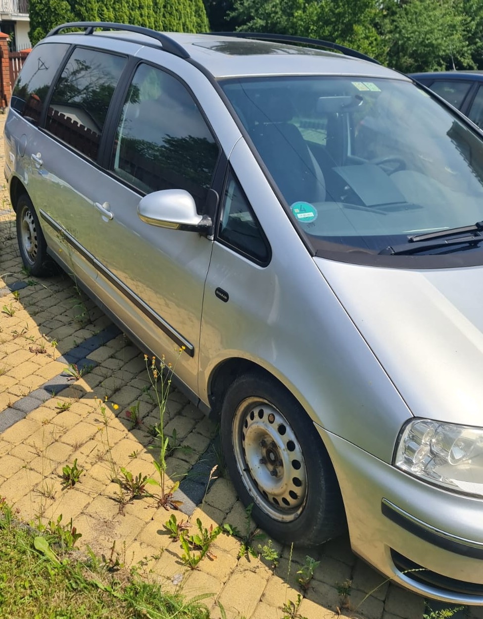 Praw bok srebrnego samochodu marki Volkswagen Sharan.