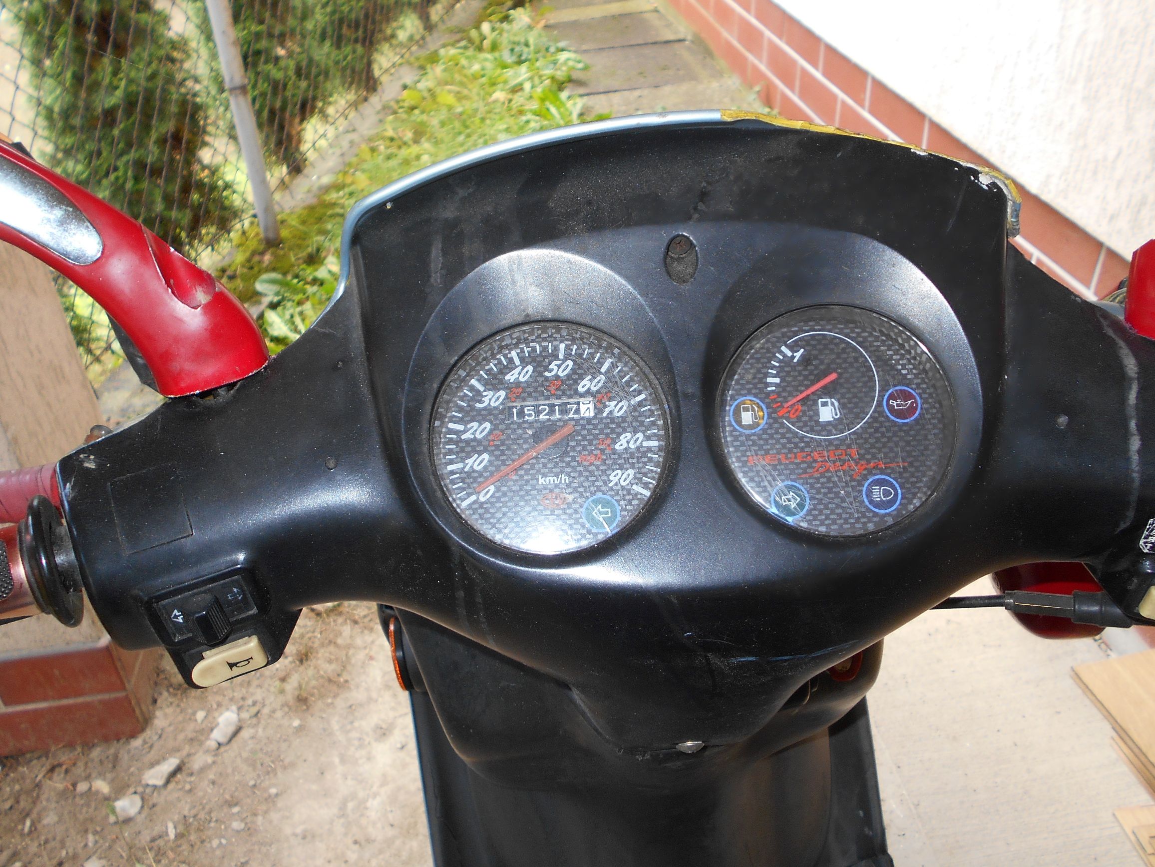 Kokpit skutera z prędkościomierzem i wskaźnikiem poziomu paliwa , na którym widoczny jest przebieg 15217 km.