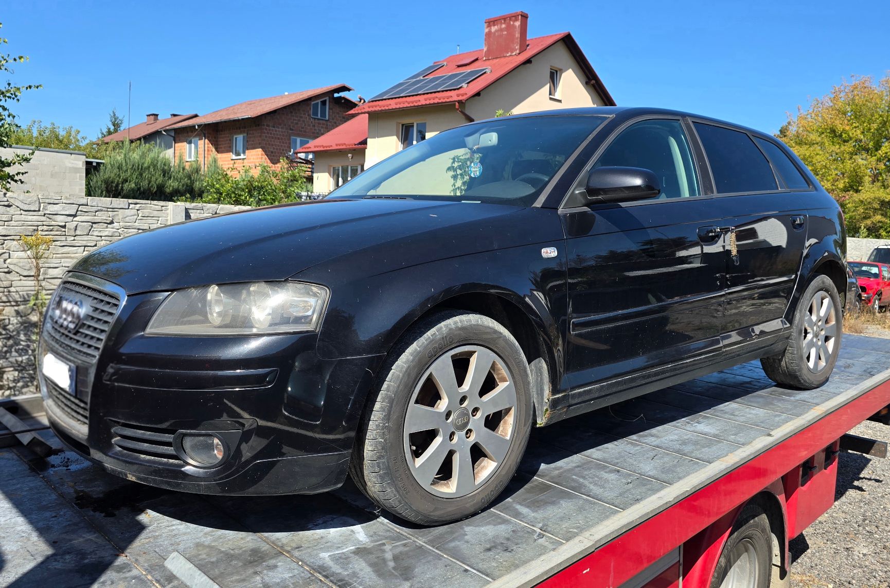 Granatowy samochód Audi A3. Widok od strony lewego profilu.