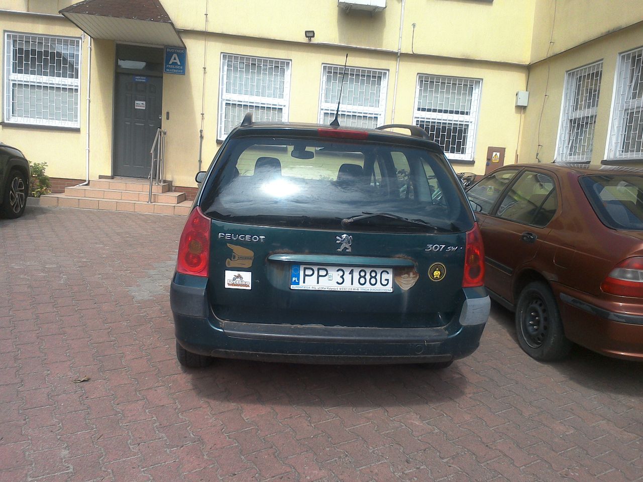 Widok zielonego Peugeota 307 z tyłu. Widoczne liczne ogniska korozji.
