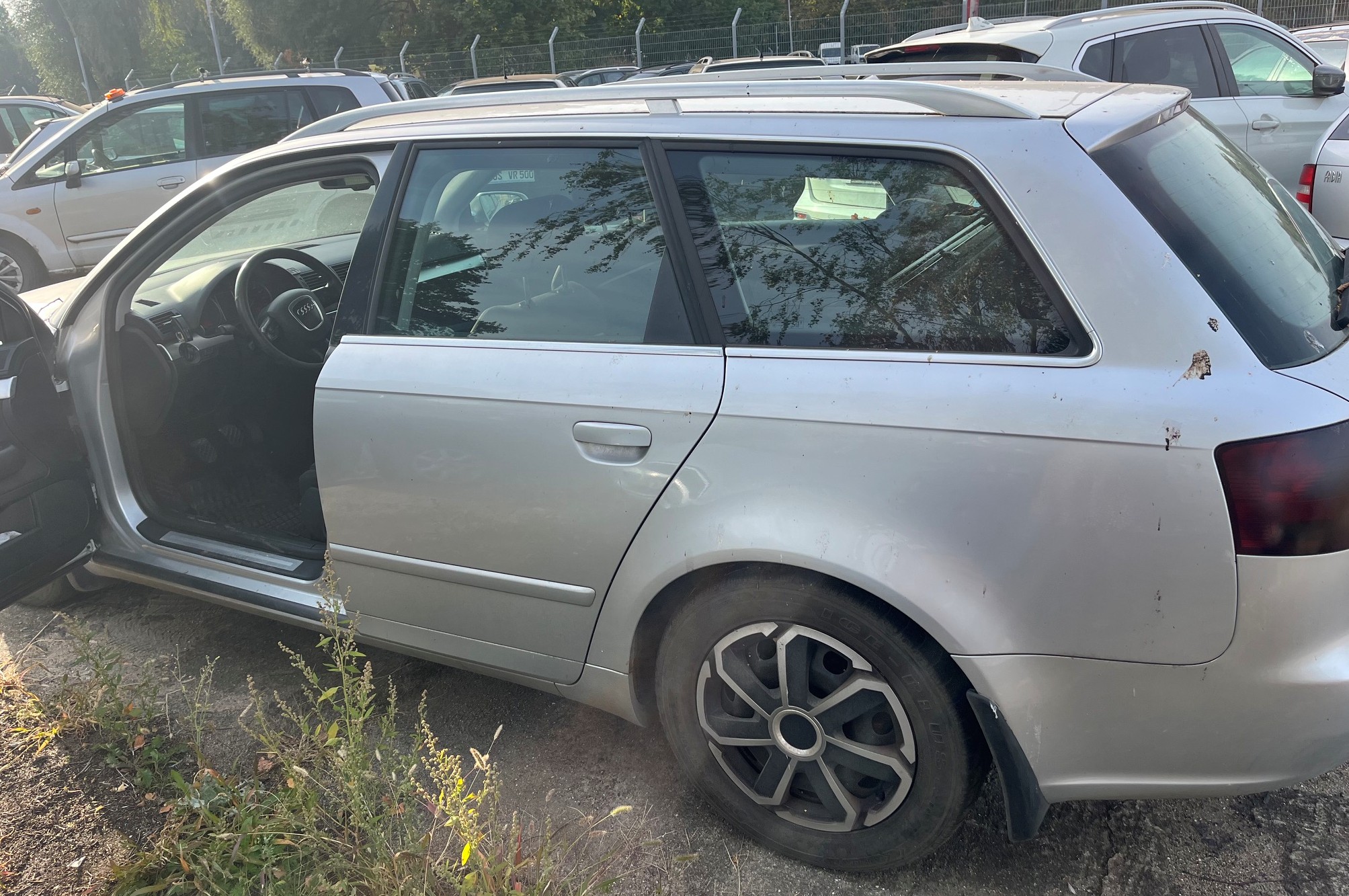 Srebrne Audi A4 kombi, widok z lewego boku z otwartymi drzwiami kierowcy.