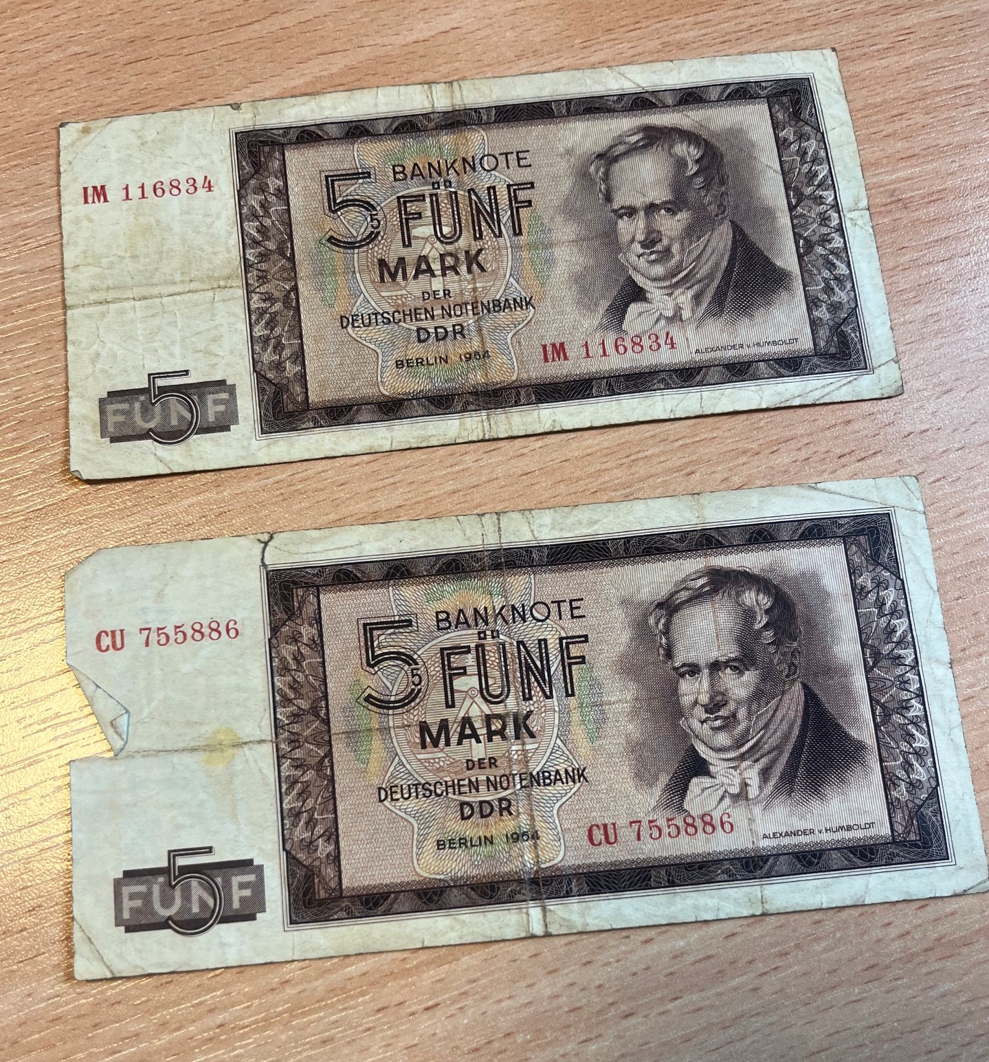 Awersy dwóch banknotów o nominale 5 marek NRD z emisji z 1964 roku (Berlin 1964), ułożone pionowo jeden pod drugim.