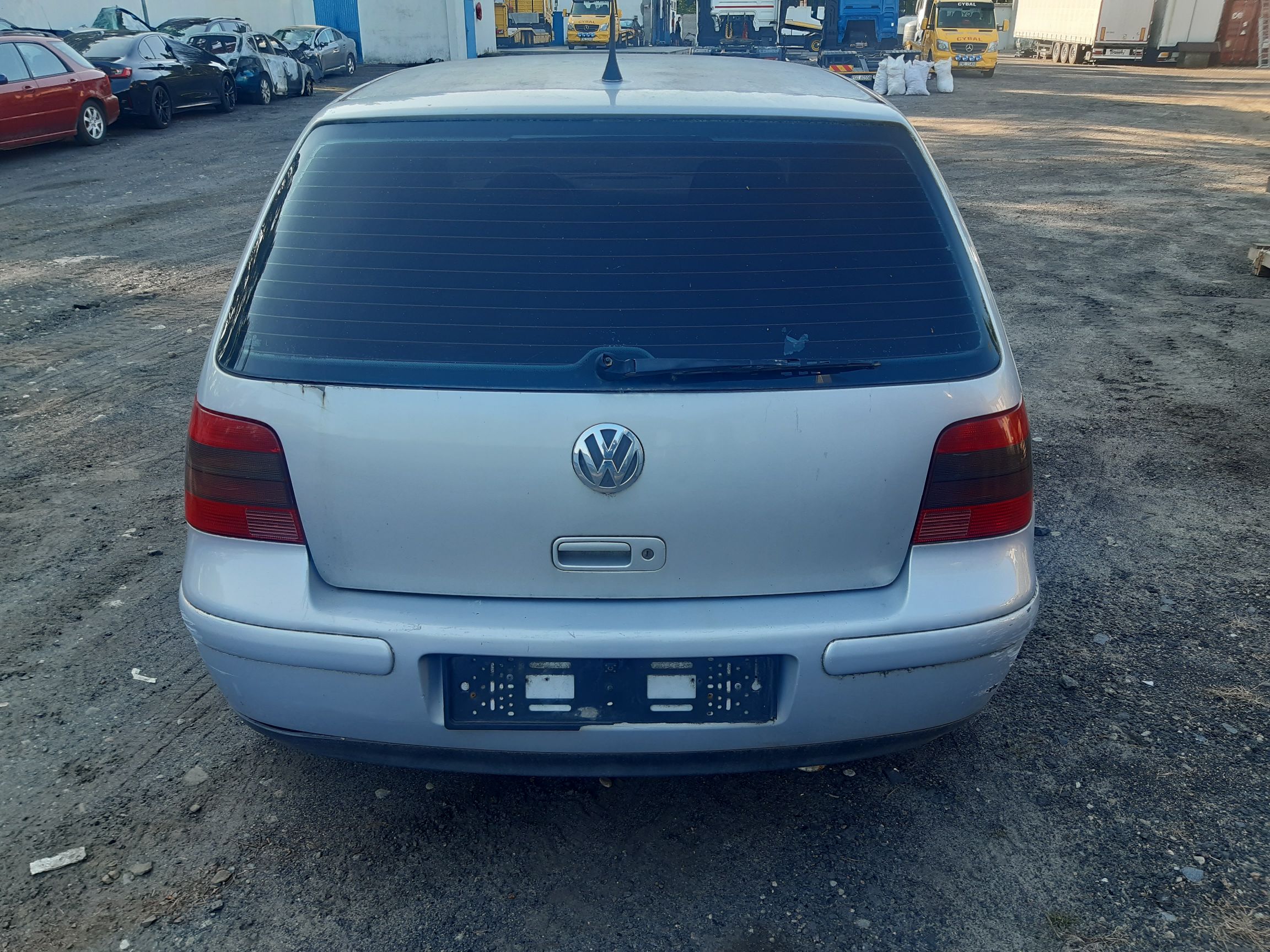 Srebrny tył Volkswagena Golfa IV z widocznym logo marki, wycieraczką i ramką na tablicę rejestracyjną.