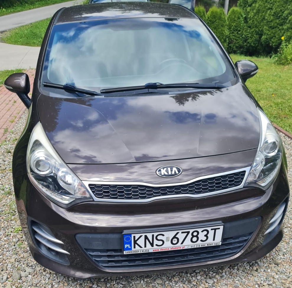 Brązowy Kia Rio, widok z przodu, z wyraźnymi liniami nadwozia i stylowymi reflektorami.