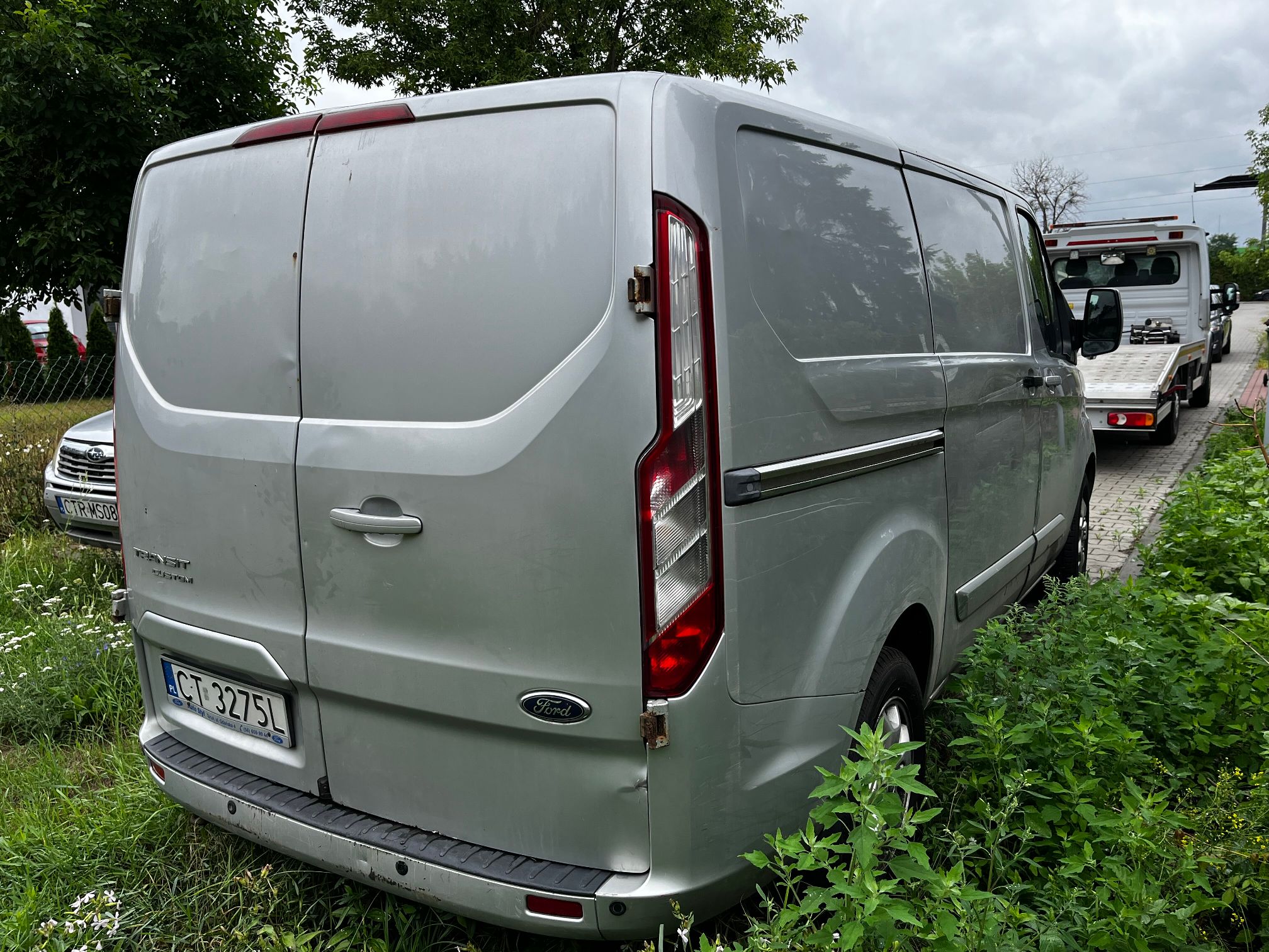 srebrny Ford Transit Custom widać bok od strony pasażera zarysowany po całej długości i lekko wgniecony