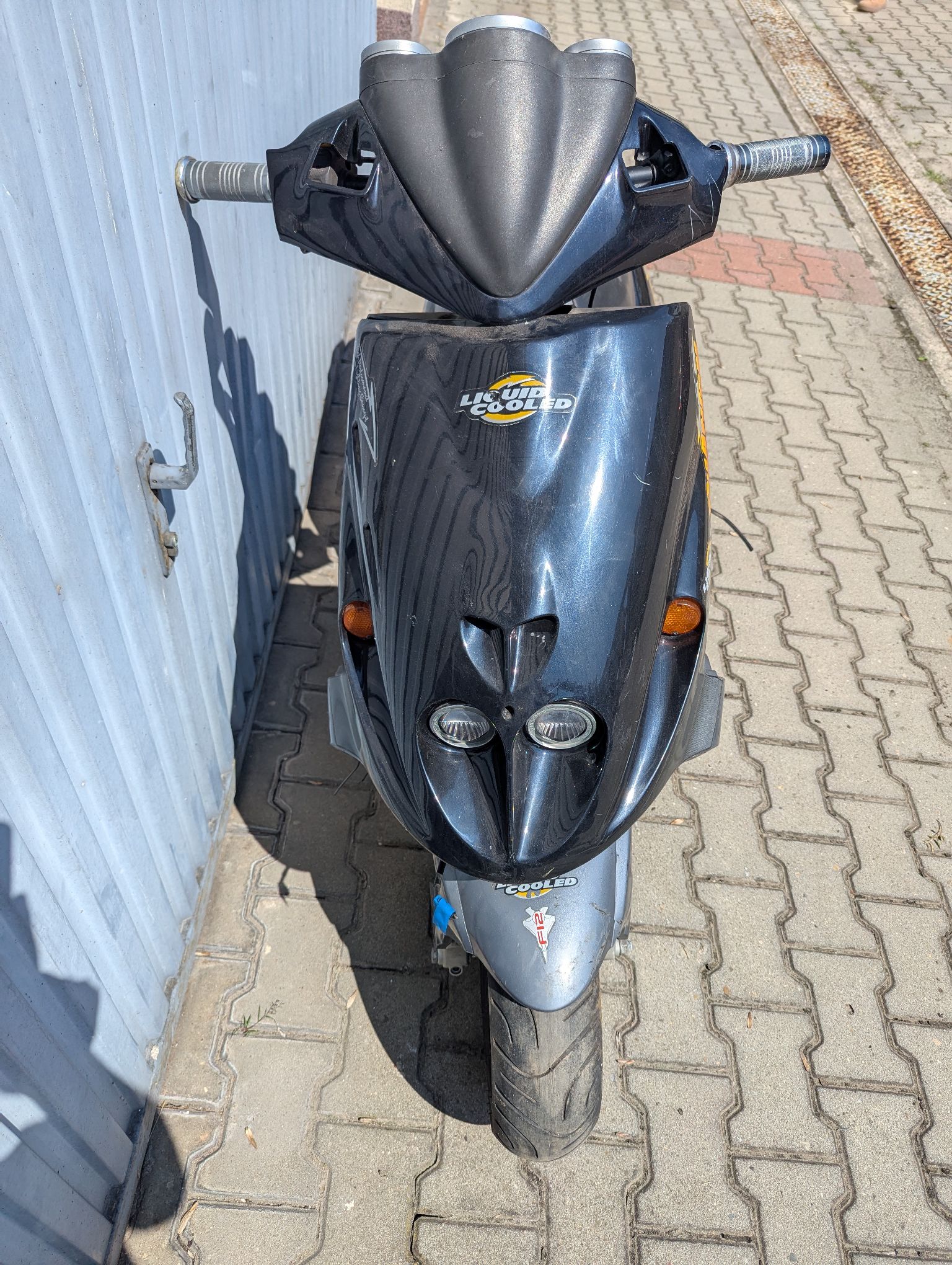 Przód czarnego motoroweru Malaguti. Owiewki w dobrym stanie, brak lusterek