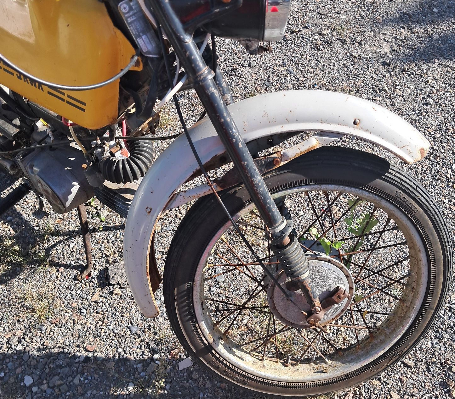 Widoczne jest przednie koło motoroweru wraz z błotnikiem