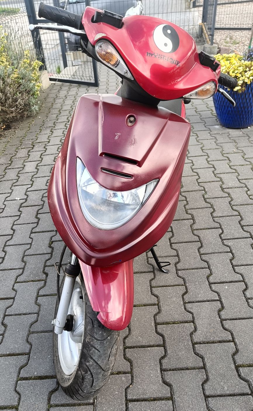 Przód motoroweru w kolorze czerwonym, widoczne zadrapania na obudowach pojazdu oraz pęknięcie błotnika.