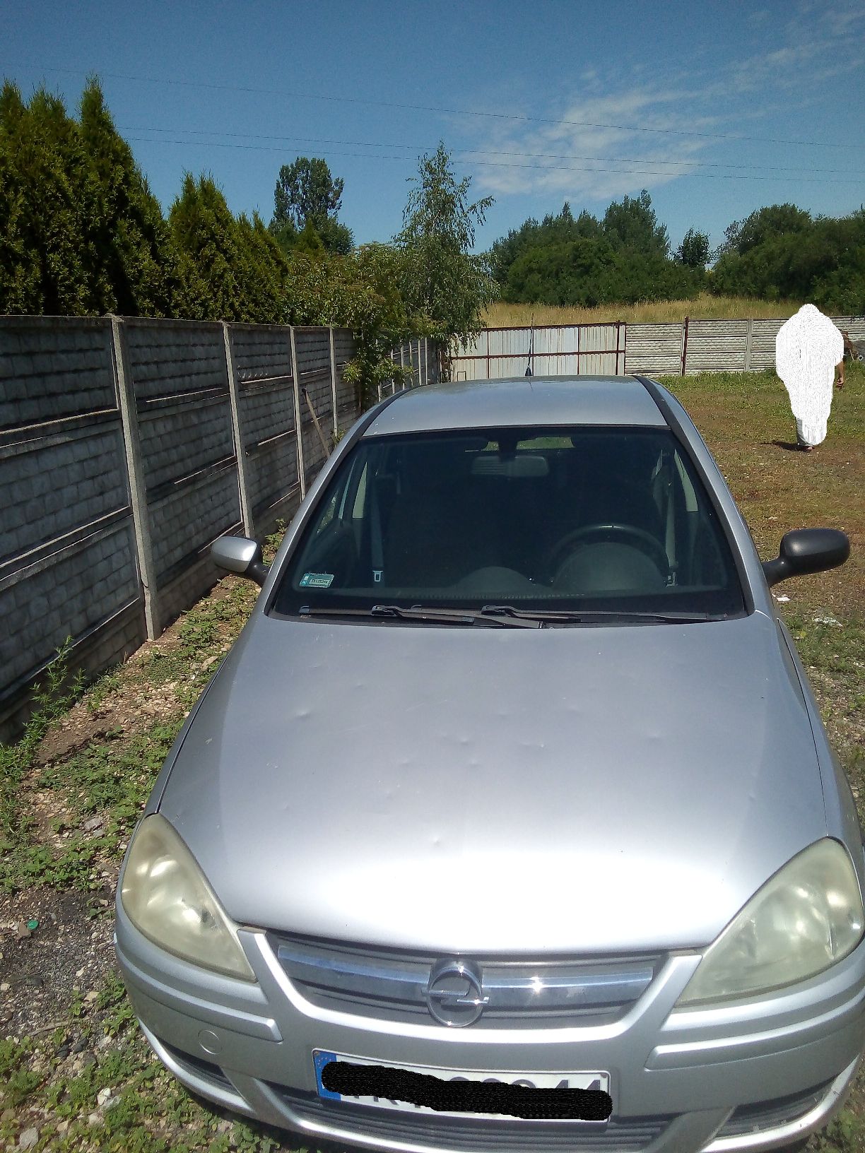 Srebrny samochód osobowy marki Opel Corsa widziany z przodu, na karoserii widoczne wgniecenia po gradobiciu