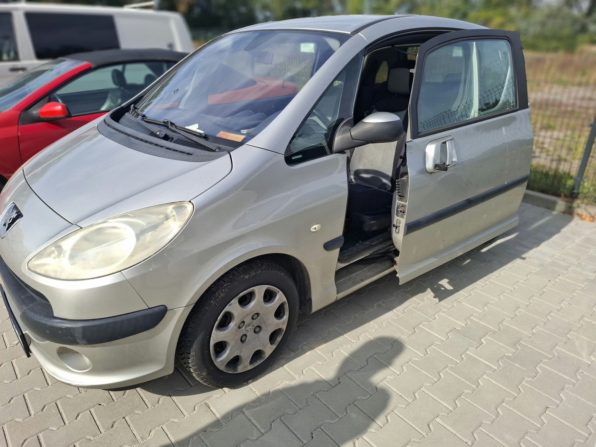 Zdjęcie lewego boku samochodu osobowego PEUGEOT 1007, wraz z otwartymi drzwiami przesuwnymi.
