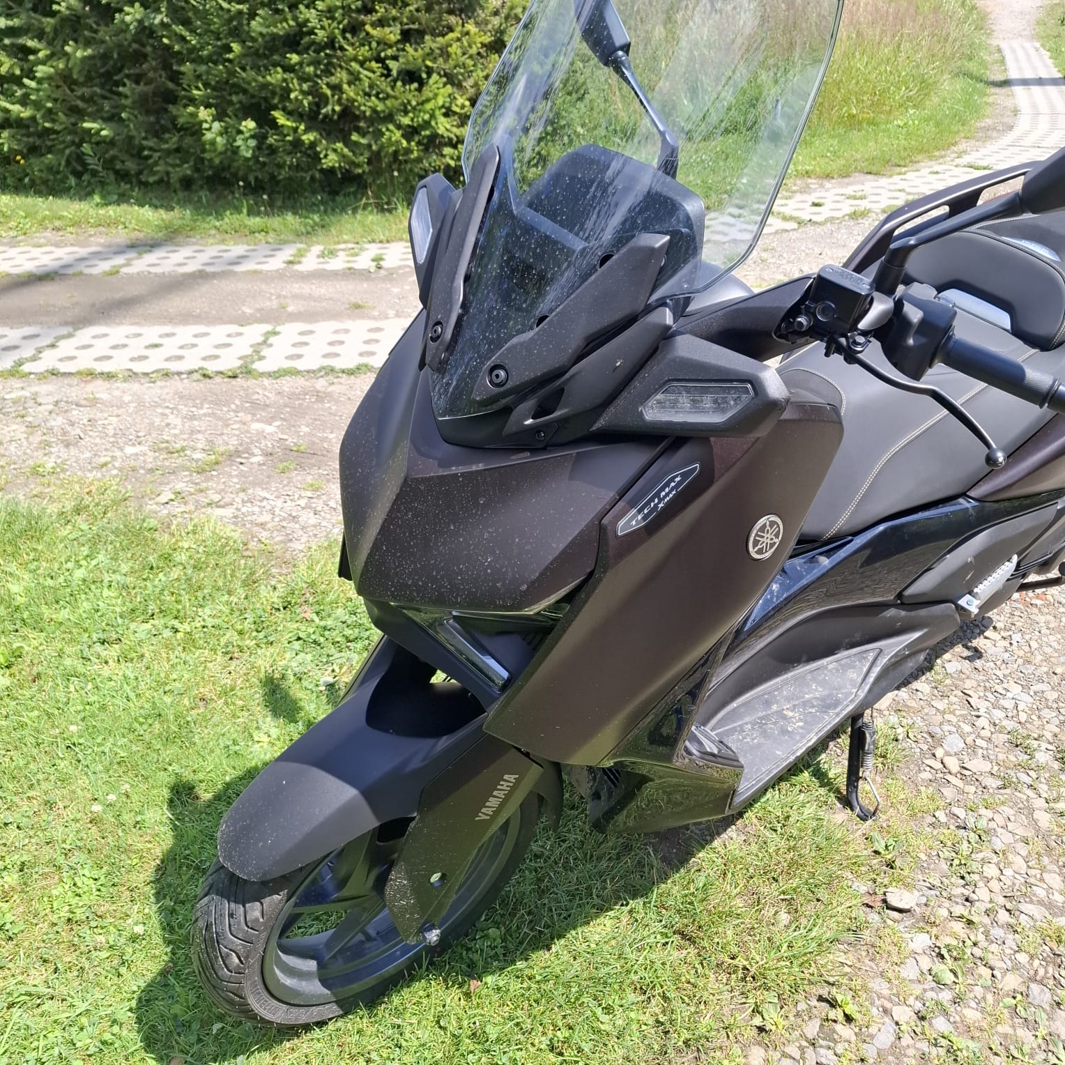 Czarny skuter Yamaha z dużą szybą i matowym wykończeniem.
