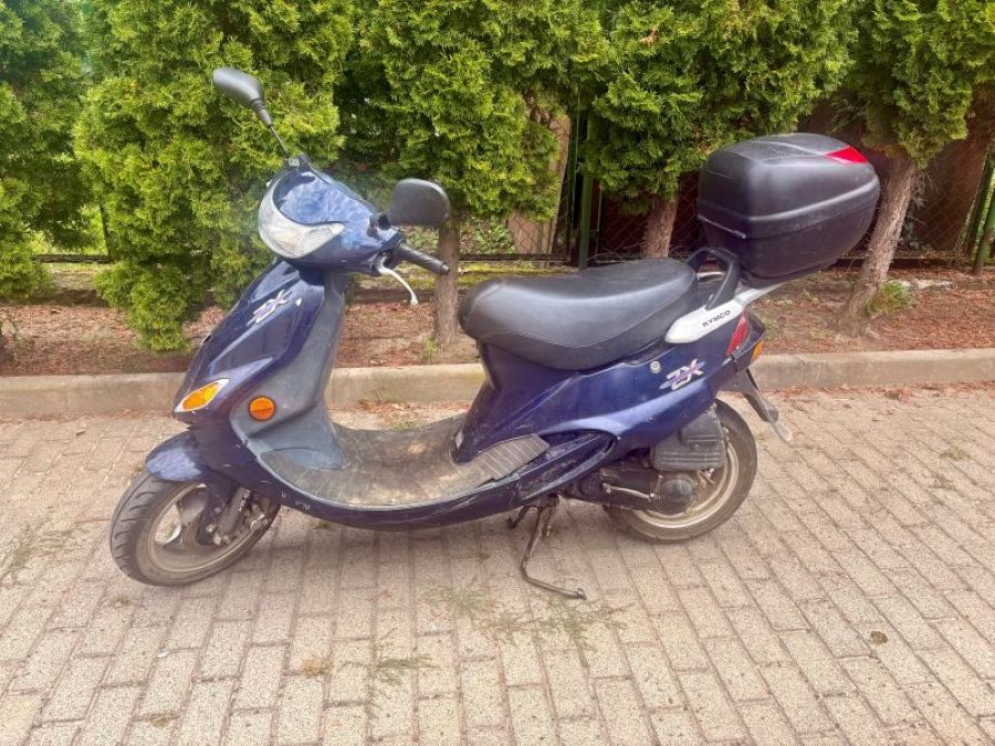 Granatowy motorower z czarnym siedzeniem z tylnym kufrem do przechowywania. widok z przodu.