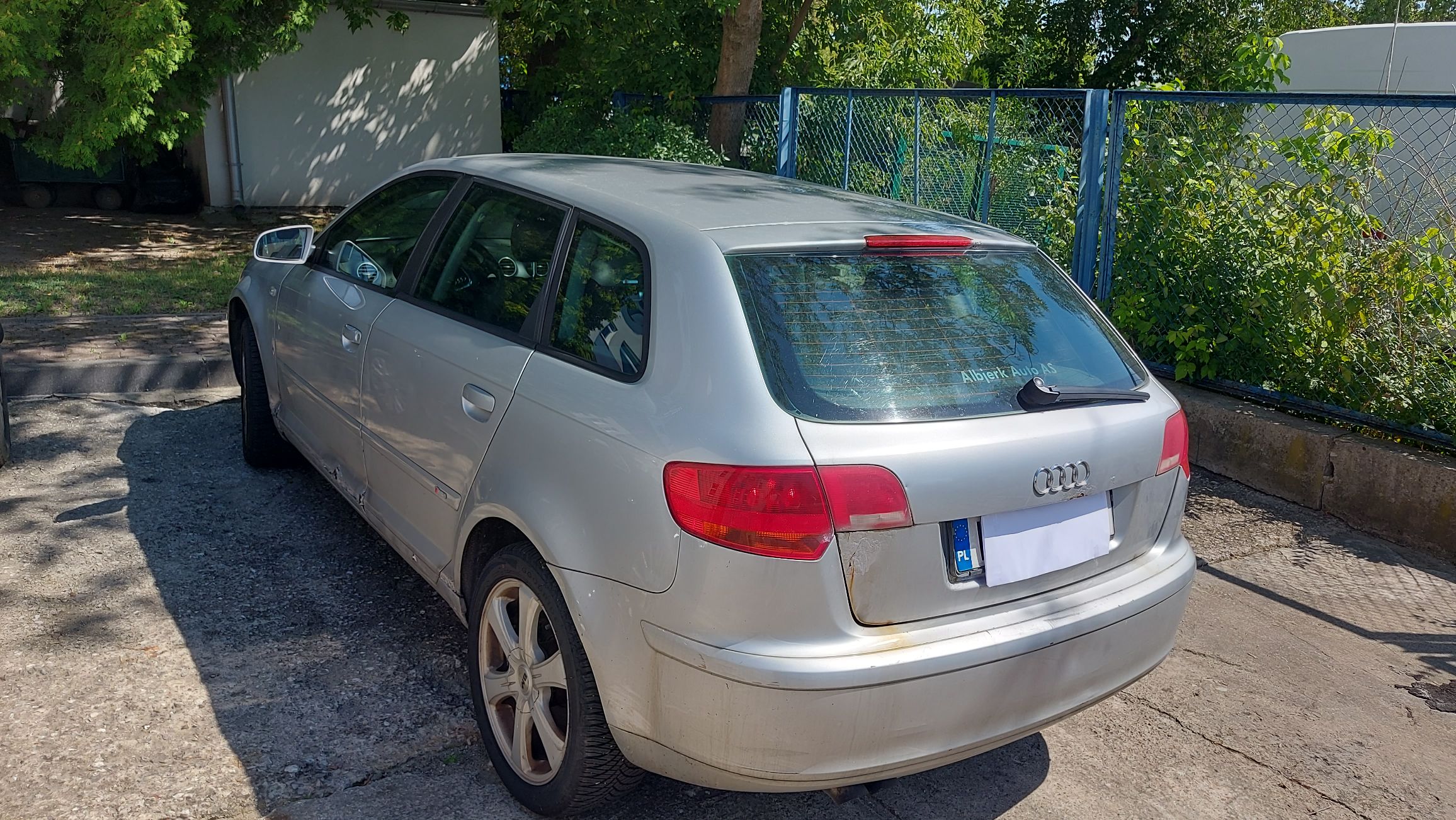 Audi A3 od strony bagażnika, widoczna klapa z logo, tylna szyba z wycieraczką oraz lewy bok pojazdu.