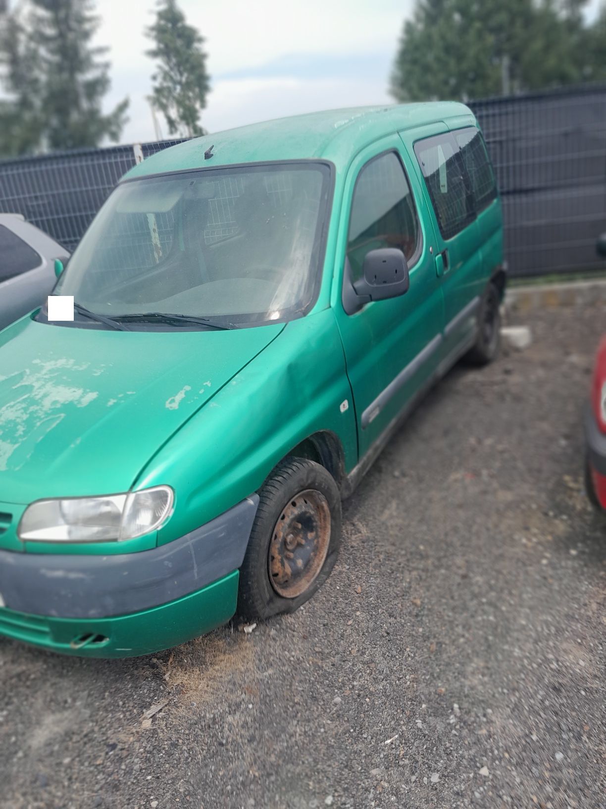 Zielony Citroen Berlingo, widziany od lewej strony, brak powietrza w kole przednim