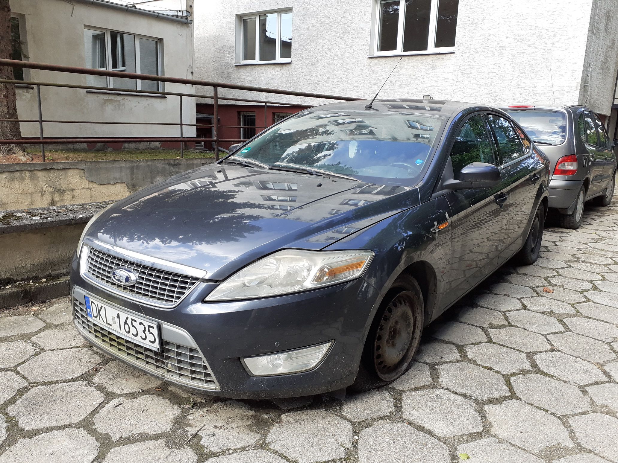 Przód pojazdu Ford Mondeo w kolorze granatowym; widoczna uszkodzona lewa opona.