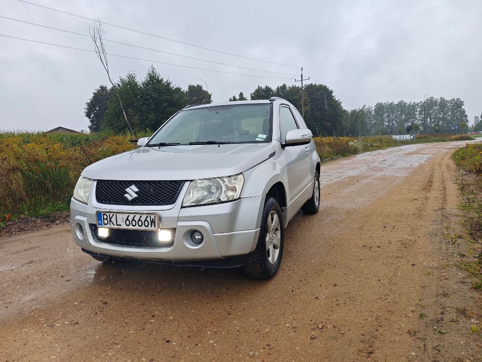 Srebrny samochód marki Suzuki Grand Vitara II w wersji trzydrzwiowej, lewa przednia strona