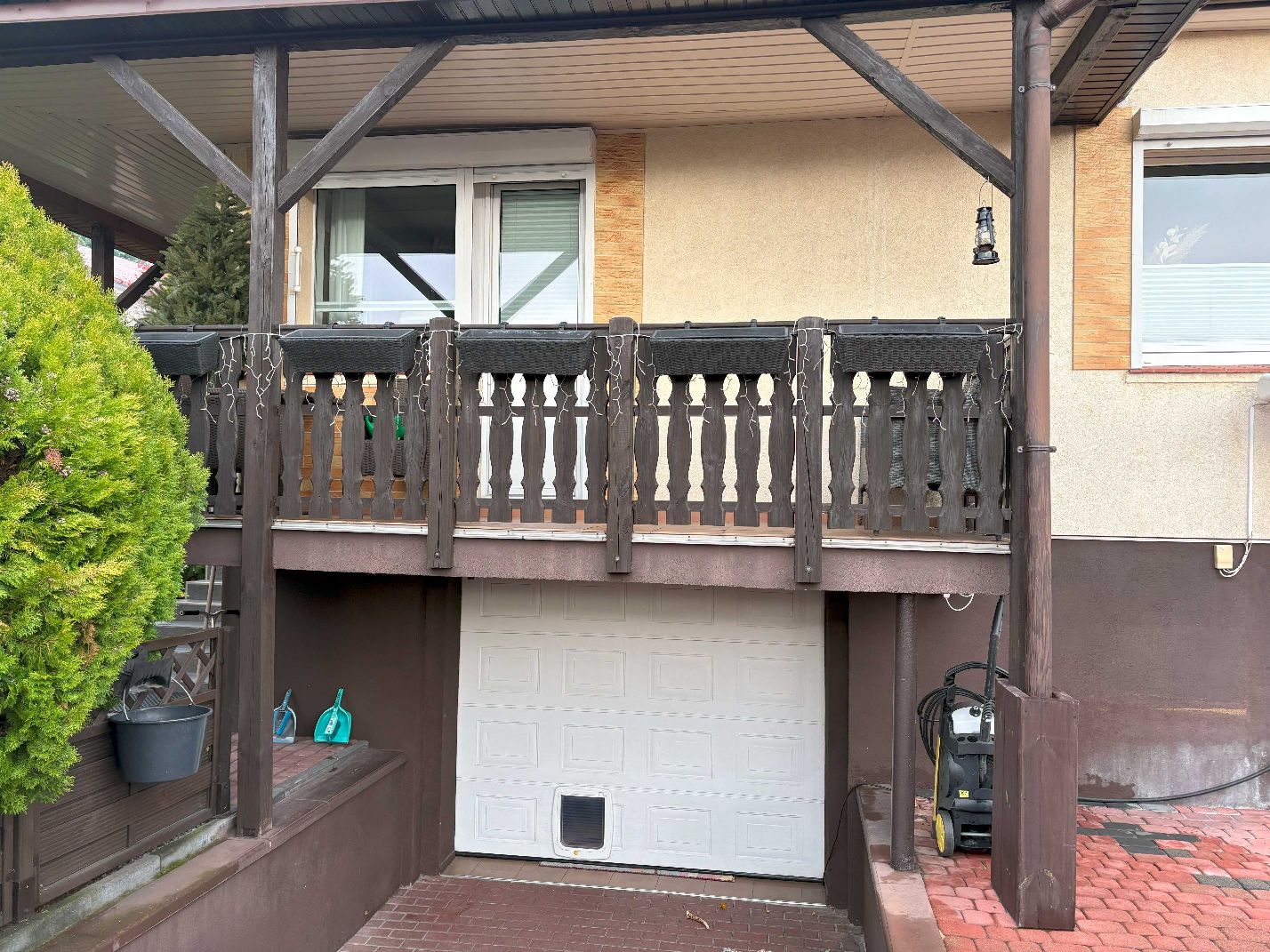 Balkon budynku mieszkalnego wraz z białą bramą segmentową do garażu pod budynkiem mieszkalny