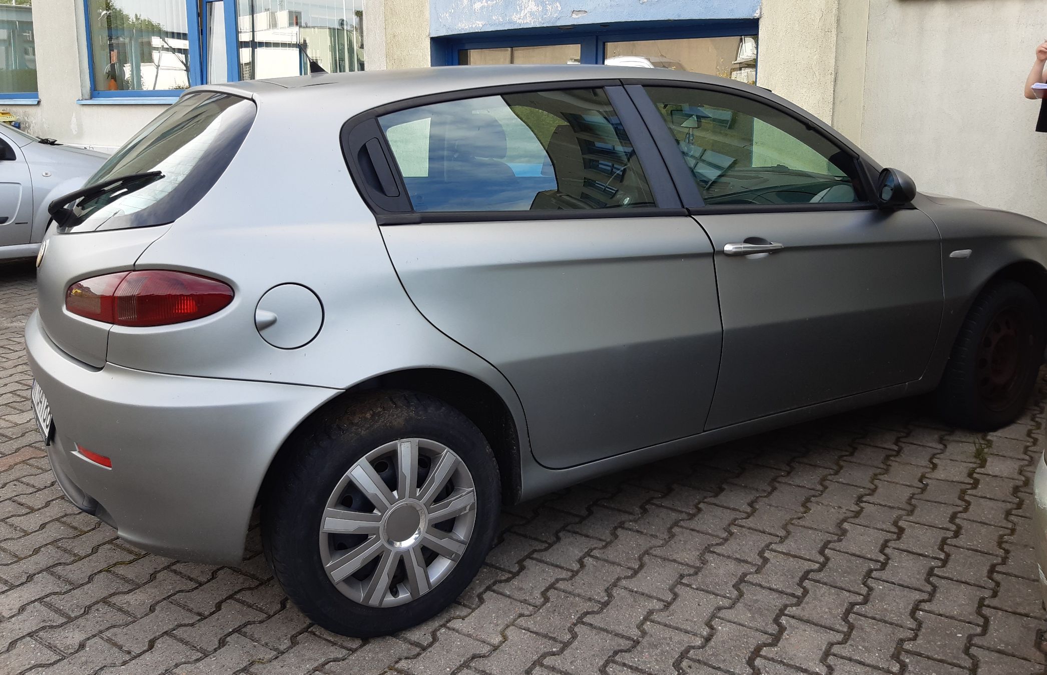 Szary pięciodrzwiowy hatchback marki Alfa Romeo model 147.