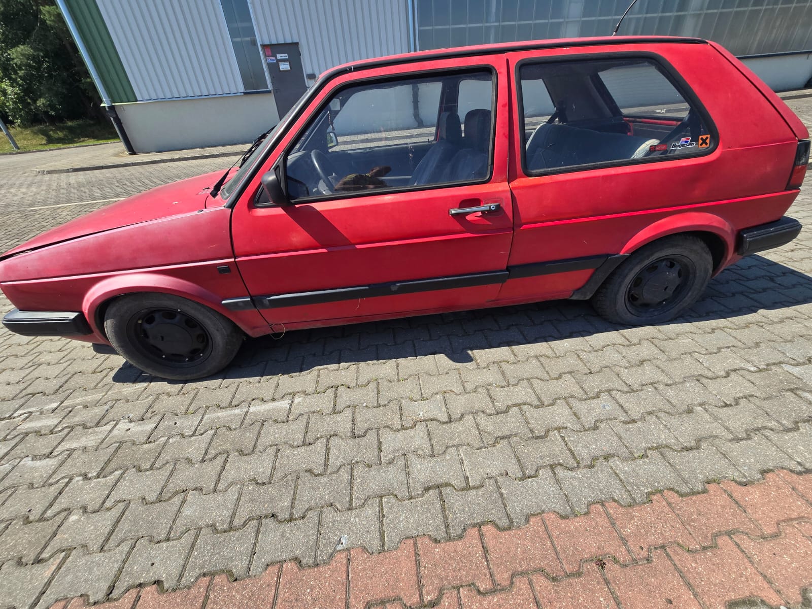 Zdjęcie lewego boku pojazdu, od strony kierowcy, maska przednia lekko podniesiona, nadkola przednie mają wyblakły kolor