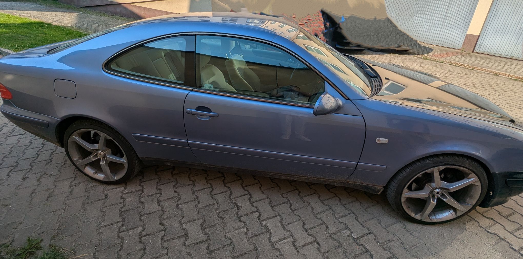 Prawa strona samochodu Mercedes-Benz CLK 200. Kolor lakieru szaro-błękitny w dobrym stanie. Samochód posiada aluminiowe felgi