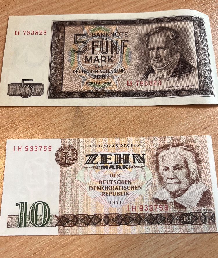 Dwa historyczne banknoty z NRD: 5 marek z 1964 roku oraz 10 marek z 1971 roku, ułożone jeden pod drugim.