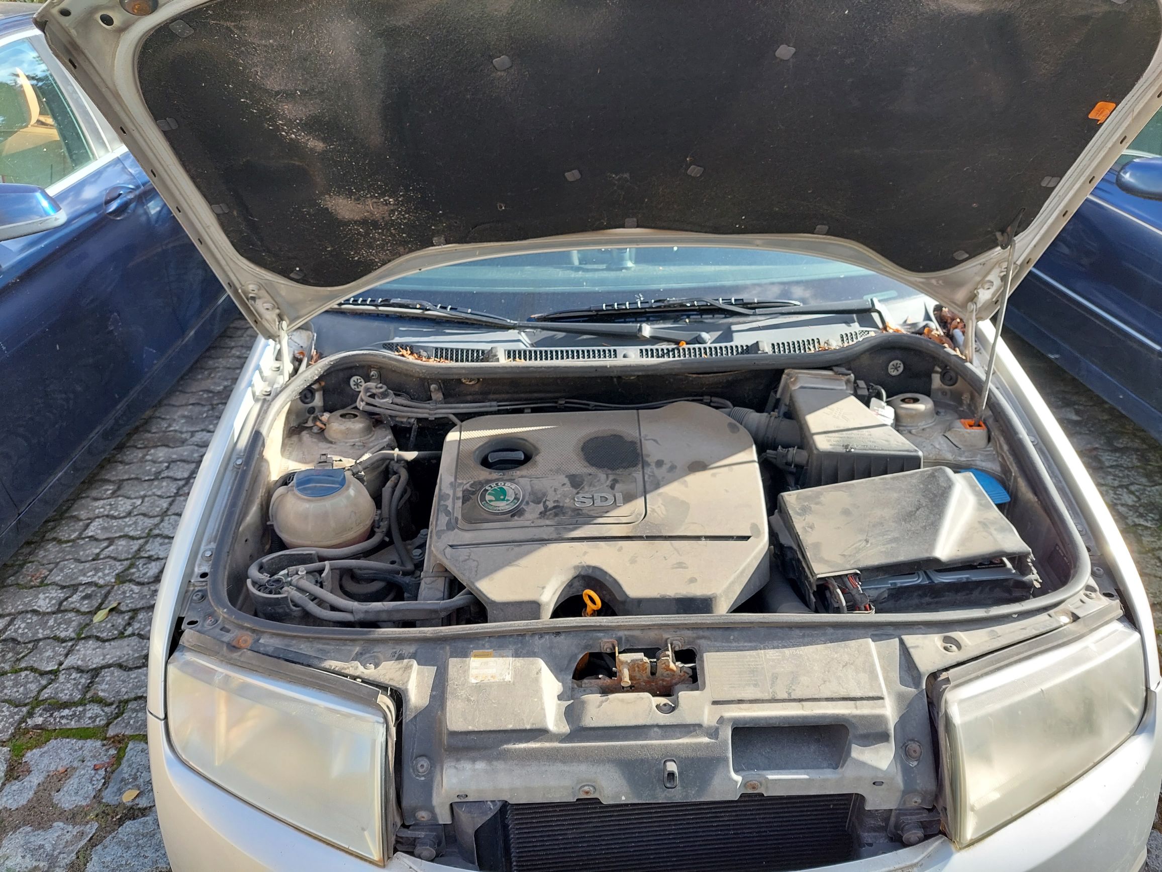 Komora silnika, zakurzona, osłona silnika ze znaczkiem SKODA i napisem SDI. Akumulator. Wizualnie kompletna bez uszkodzeń.