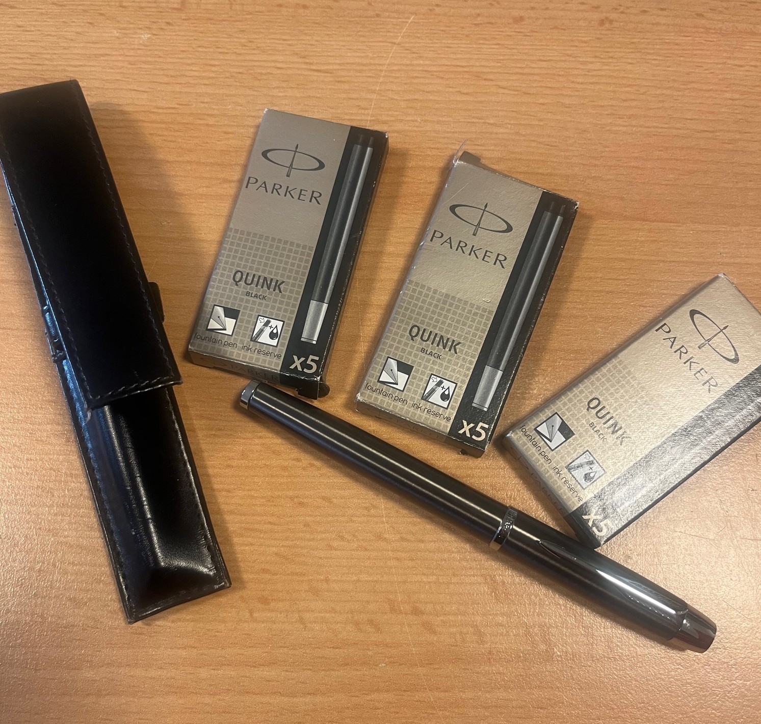 Pióro Parker leżące obok czarnego etui i wkładów Parker.