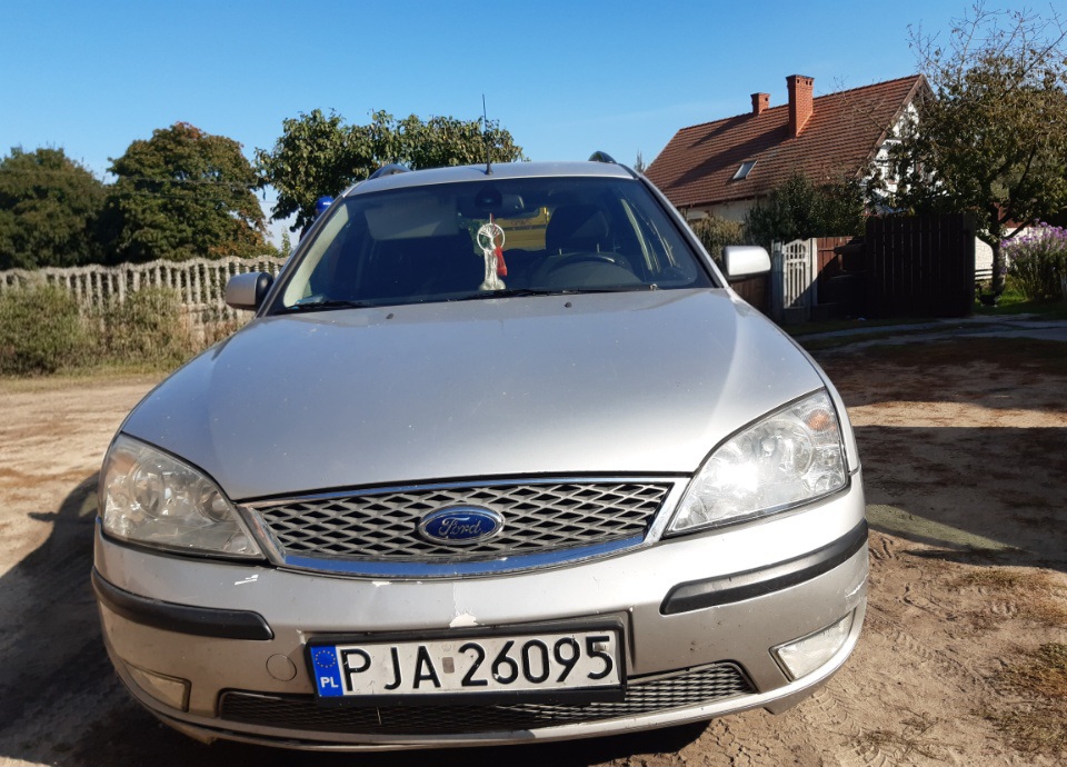 Srebrny samochód osobowy marki Ford Mondeo, zaparkowany przodem. Auto ma polską tablicę rejestracyjną PJA 26095