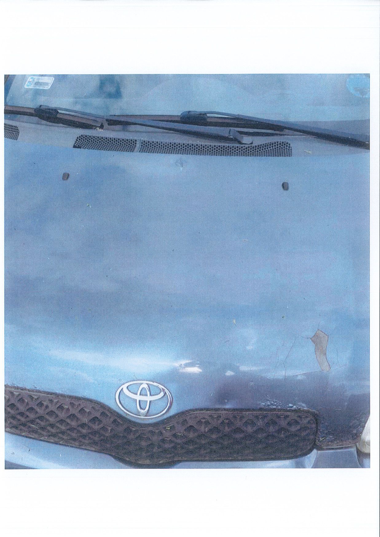 Mocno uszkodzony lakier przedniej klapy samochodu osobowego TOYOTA YARIS z widocznymi odpryskami i korozją.