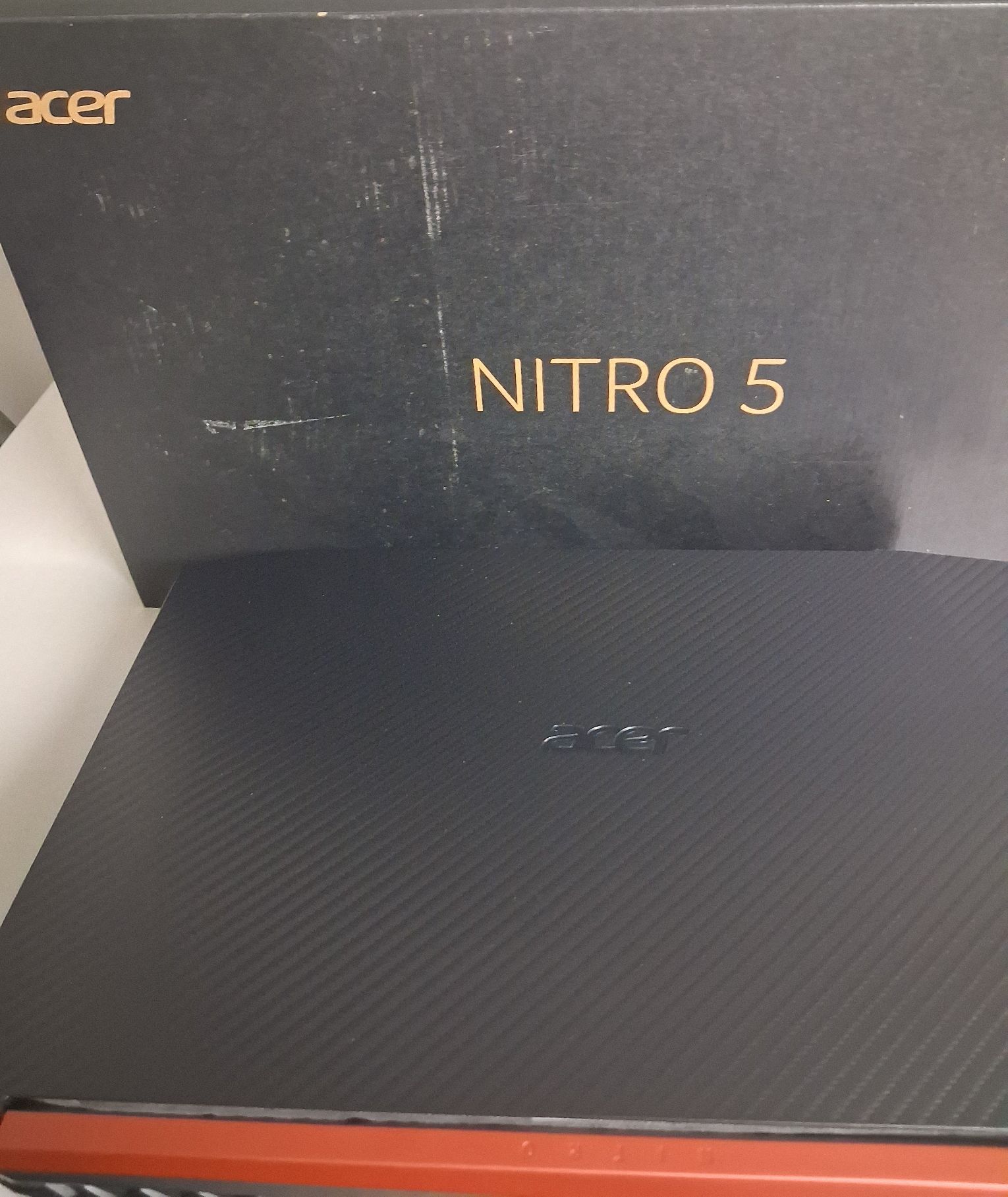 Laptop koloru czarnego z napisem ACER w opakowaniu kartonowym koloru czarnego z napisem NITRO 5.