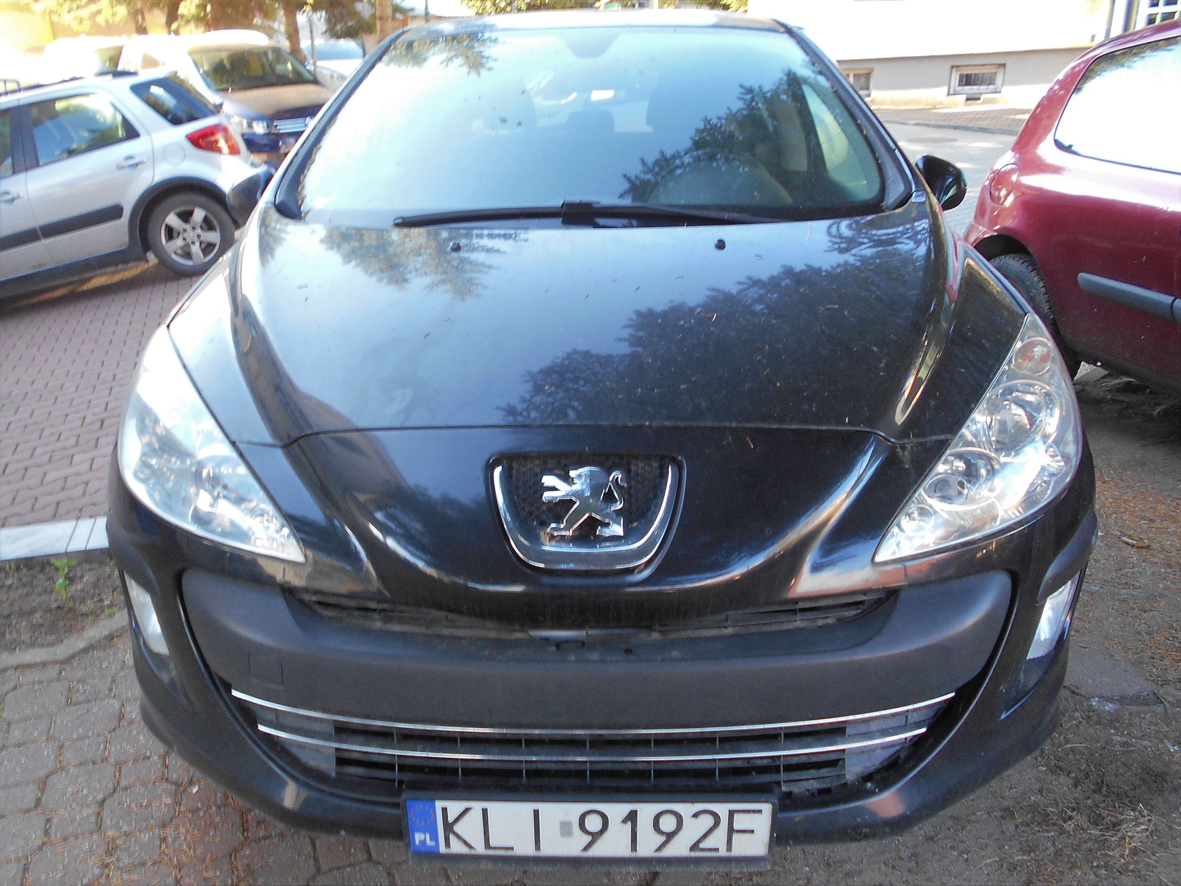 Przedni widok czarnego samochodu marki Peugeot z polską tablicą rejestracyjną.