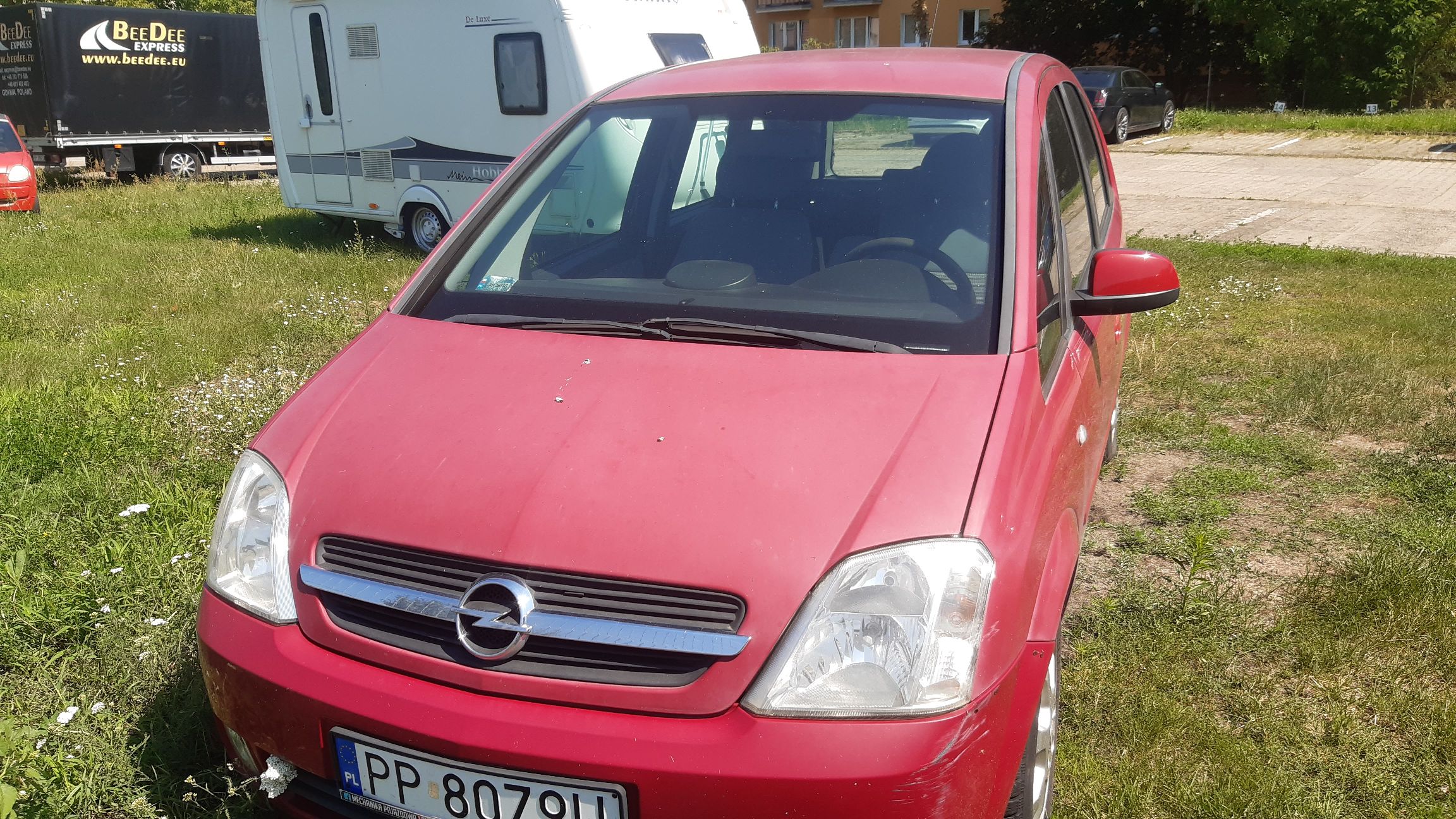 Przód czerwonego minivana z uszkodzeniami lakieru na zderzaku