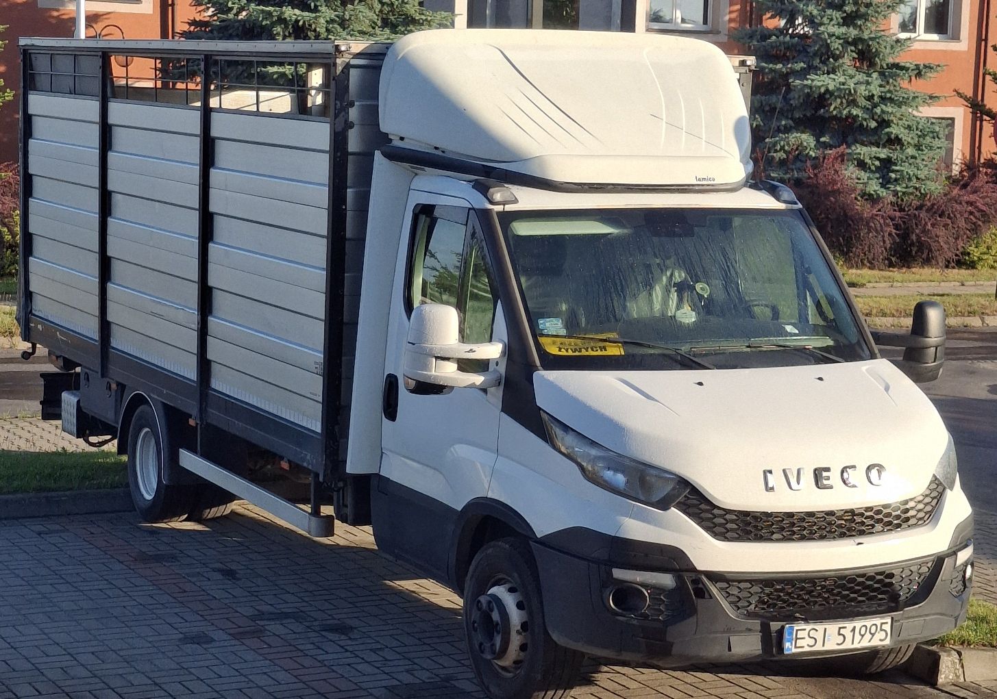 Białe Iveco Daily z prawego profilu. Duża zabudowa do przewozu zwierząt z aluminiowymi panelami.