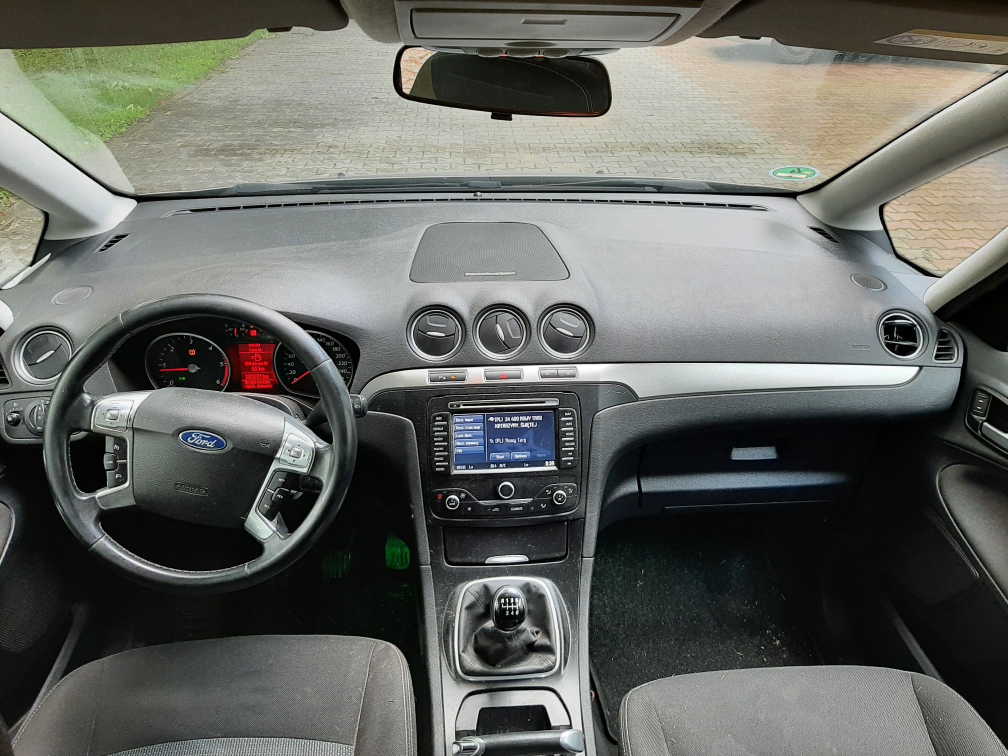 Wnętrze samochodu marki Ford, ukazująca deskę rozdzielczą, kierownicę oraz konsolę środkową z manualną skrzynią biegów